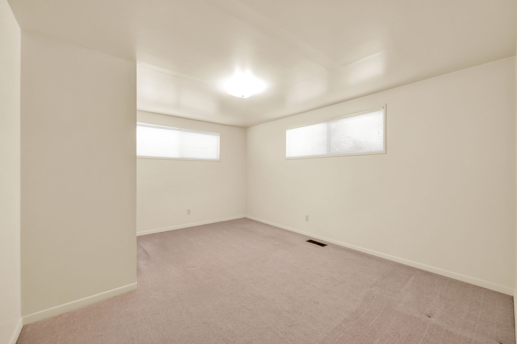 Carpeted room featuring two windows