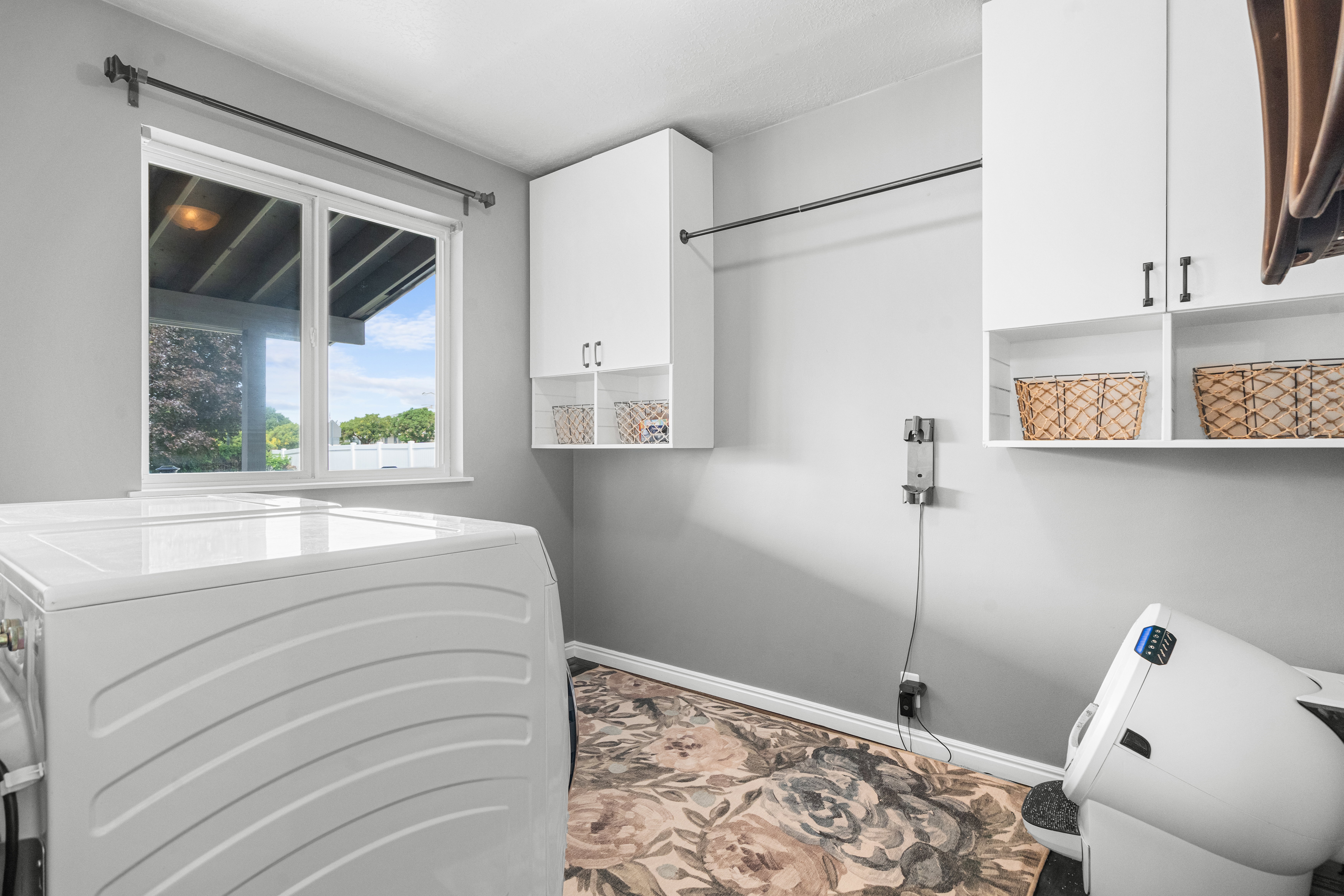 Utility laundry room with window, overhead cabinetry with laundry clothing rod
