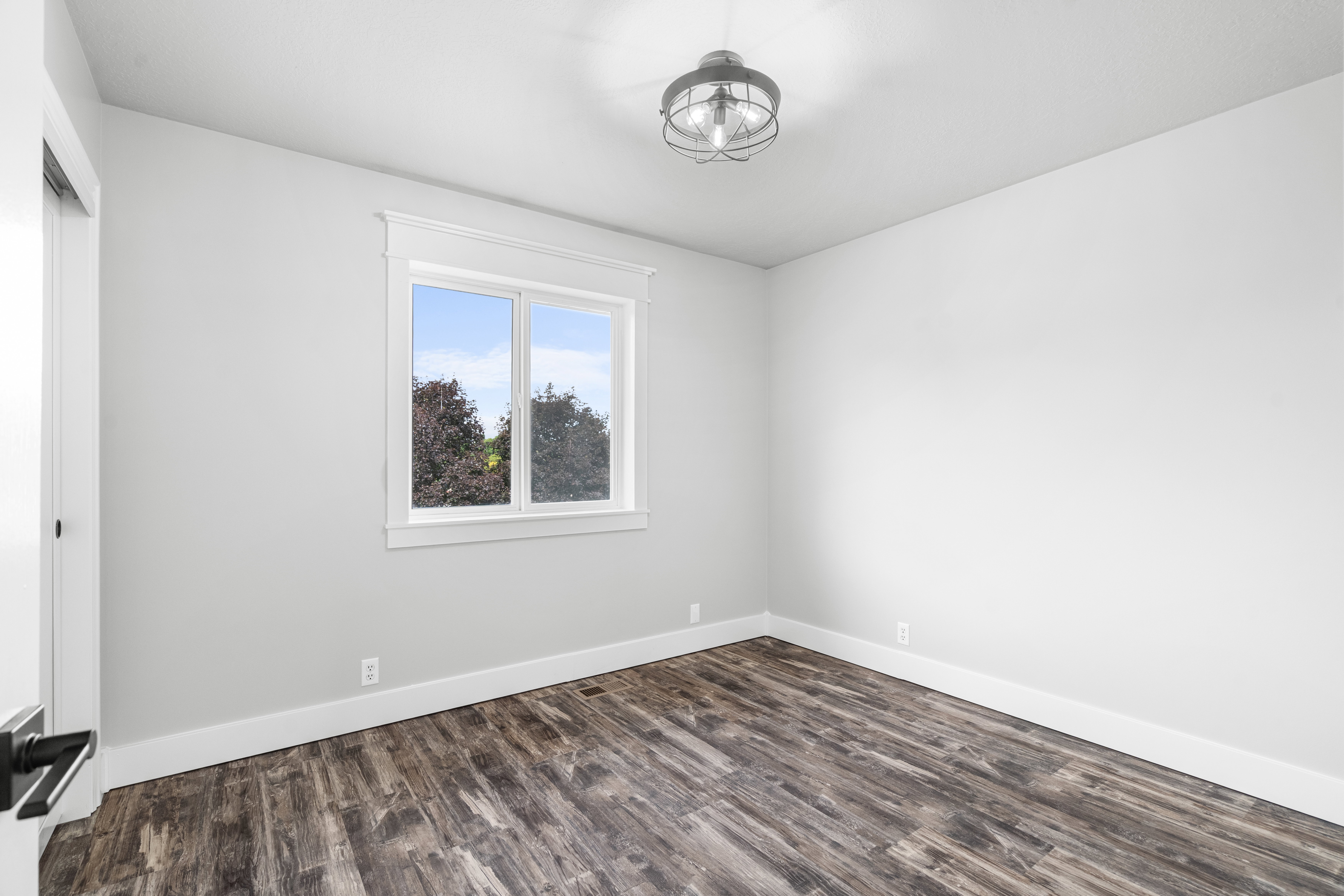 Spacious bedroom featuring LPV style flooring, white baseboards, and light gray walls