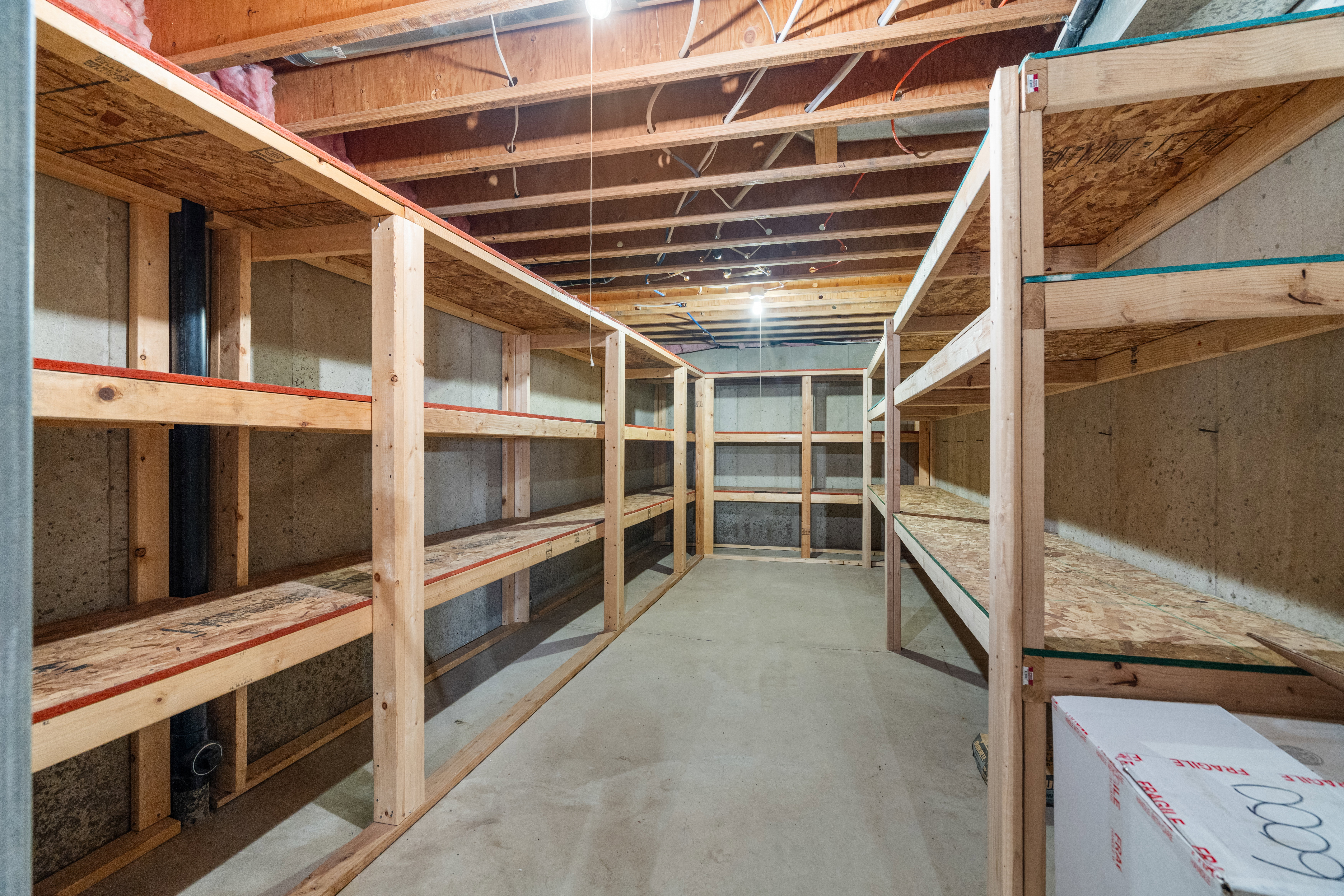 Spacious 22' x 10' cold storage room featuring extensive custom-built wood shelving that provides exceptional organization and abundant storage capacity.