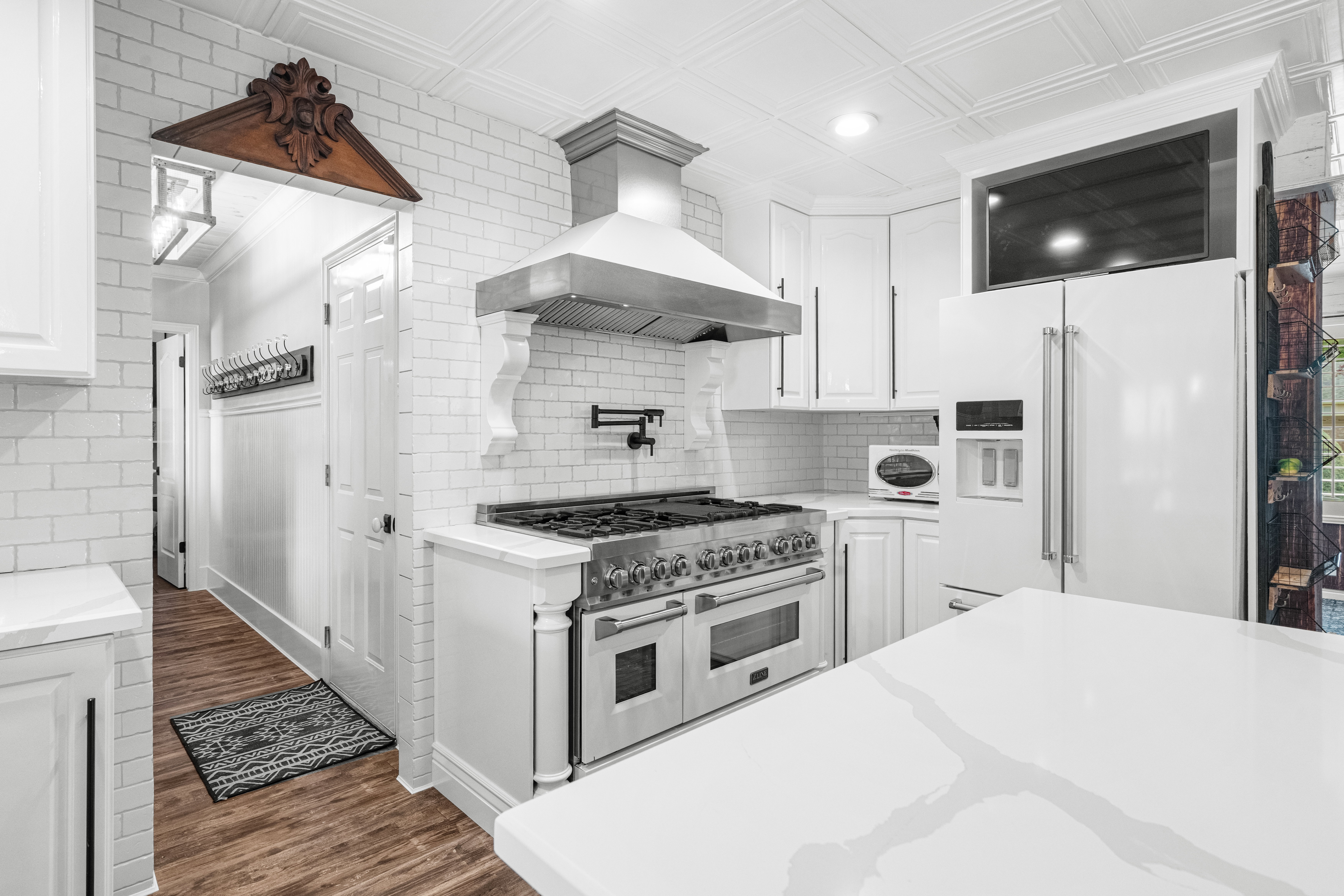 Gourmet kitchen featuring a professional-grade range, stainless steel vent hood, classic white subway tile backsplash, quartz countertops, and abundant storage, perfectly designed for both everyday living and entertaining.