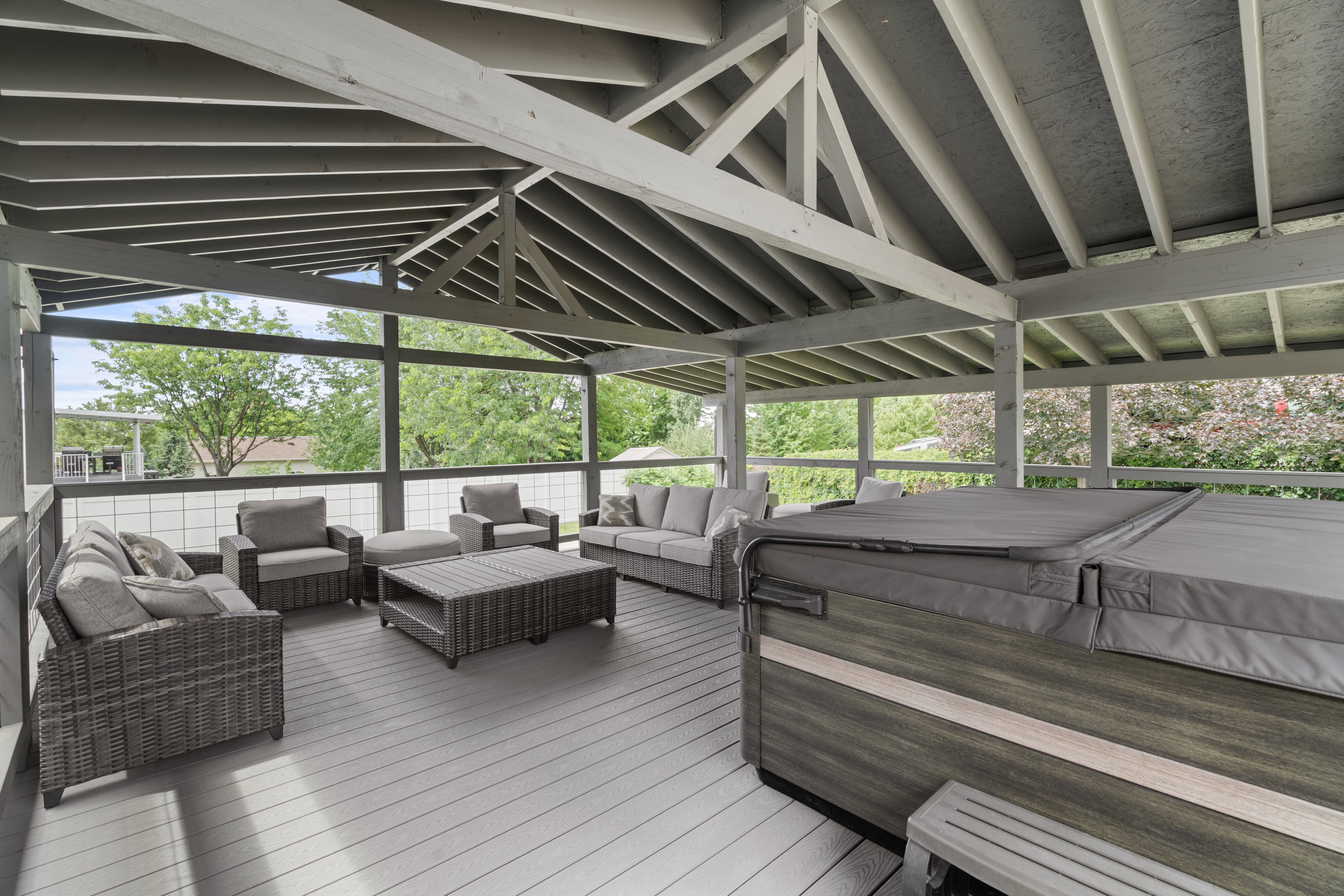 Custom-built covered gazebo deck with quality 6x6 construction, exposed beam ceiling, composite decking, and glass railings. Spacious design offers the perfect setting for outdoor gatherings and hot tub enjoyment