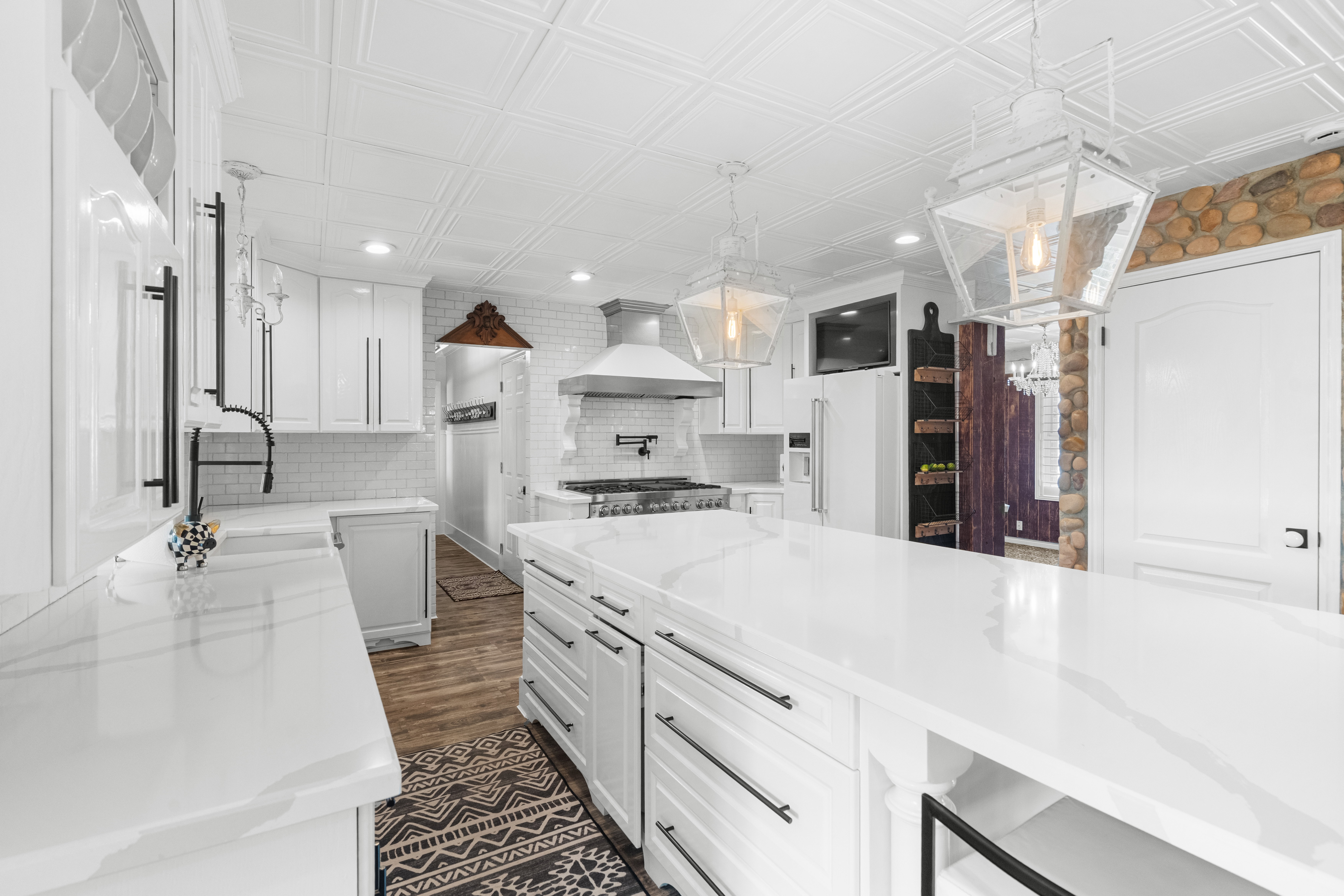 Spacious kitchen featuring white cabinetry, quartz countertops, LVP flooring, a decorative elegant ceiling, and pendant lighting
