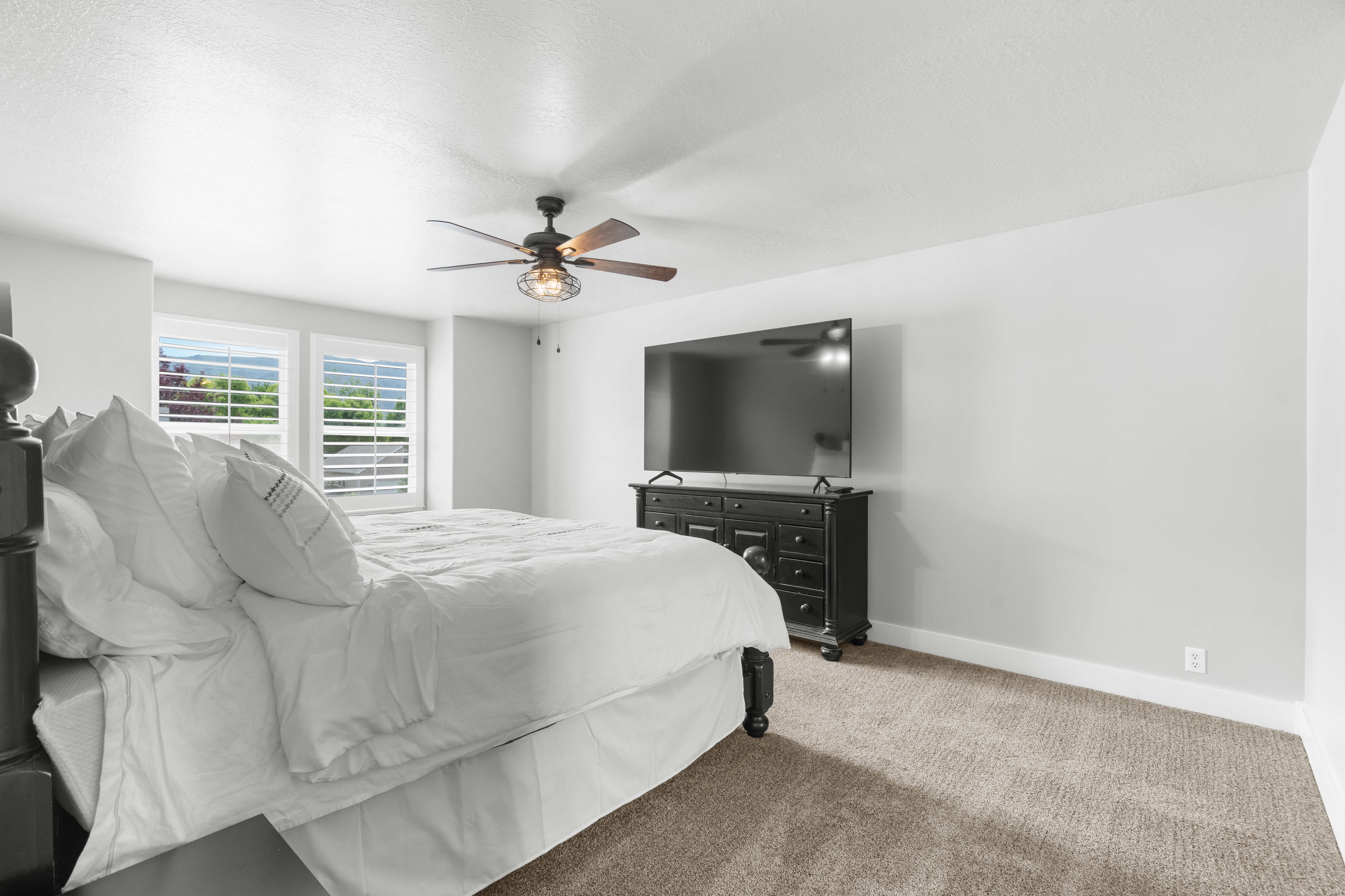 Spacious primary bedroom featuring neutral wall tones and plush carpeting, upgraded light fixtures