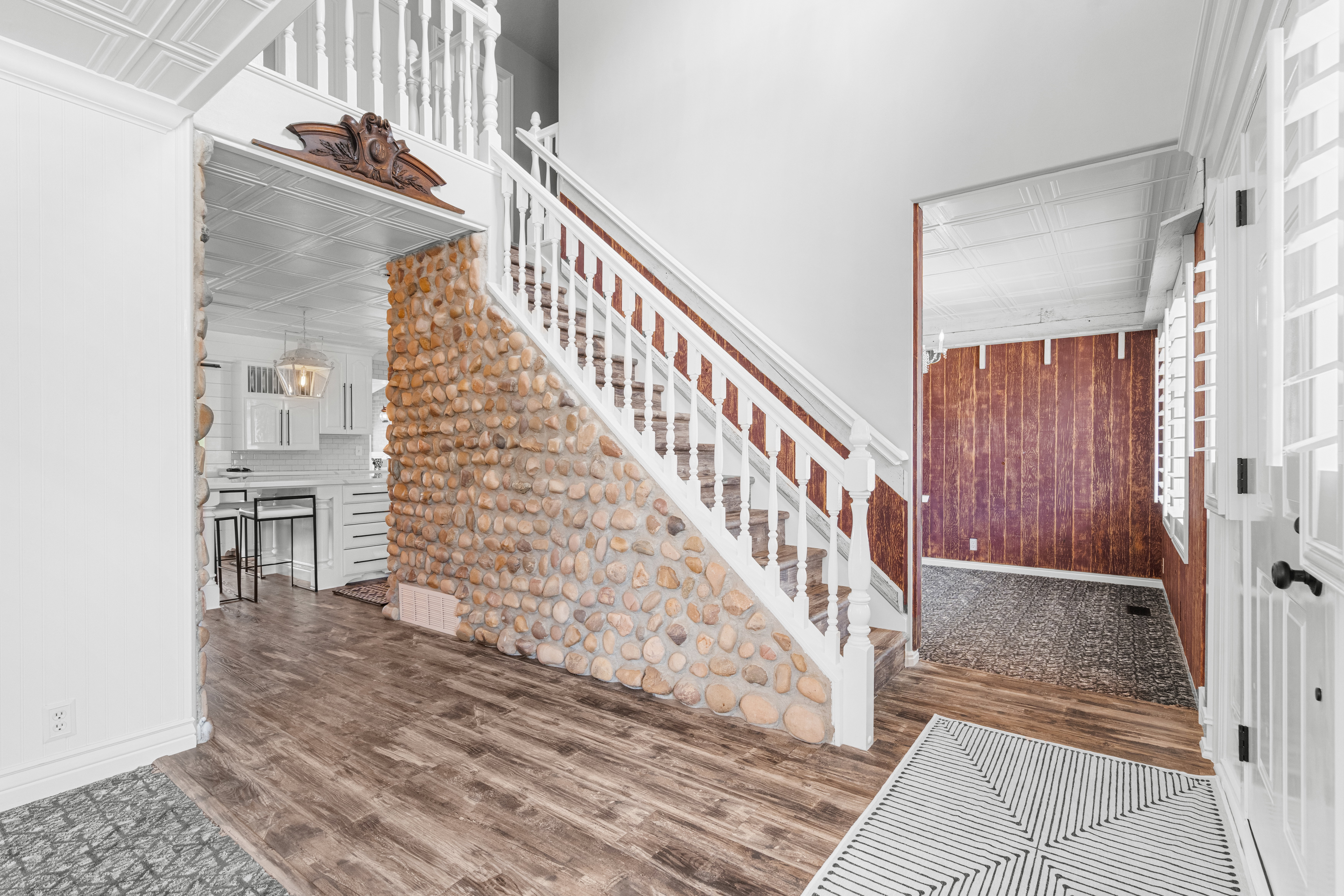 Welcoming foyer highlighted by a custom-built rock wall surrounding the staircase, adding warmth, texture, and architectural character