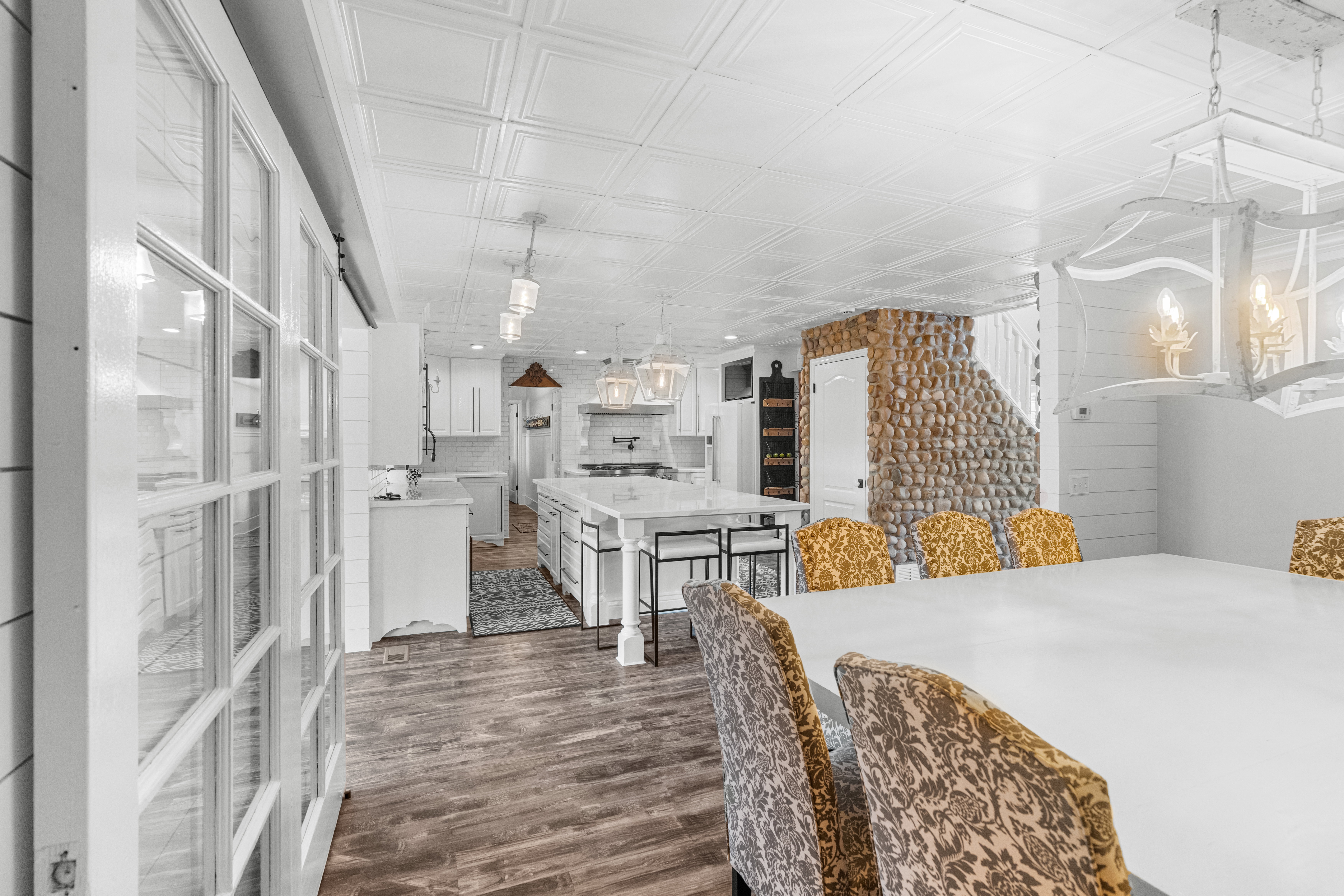 Open-concept living space featuring top of line LPV flooring, a white coffered ceiling, and a stone-clad stairwell