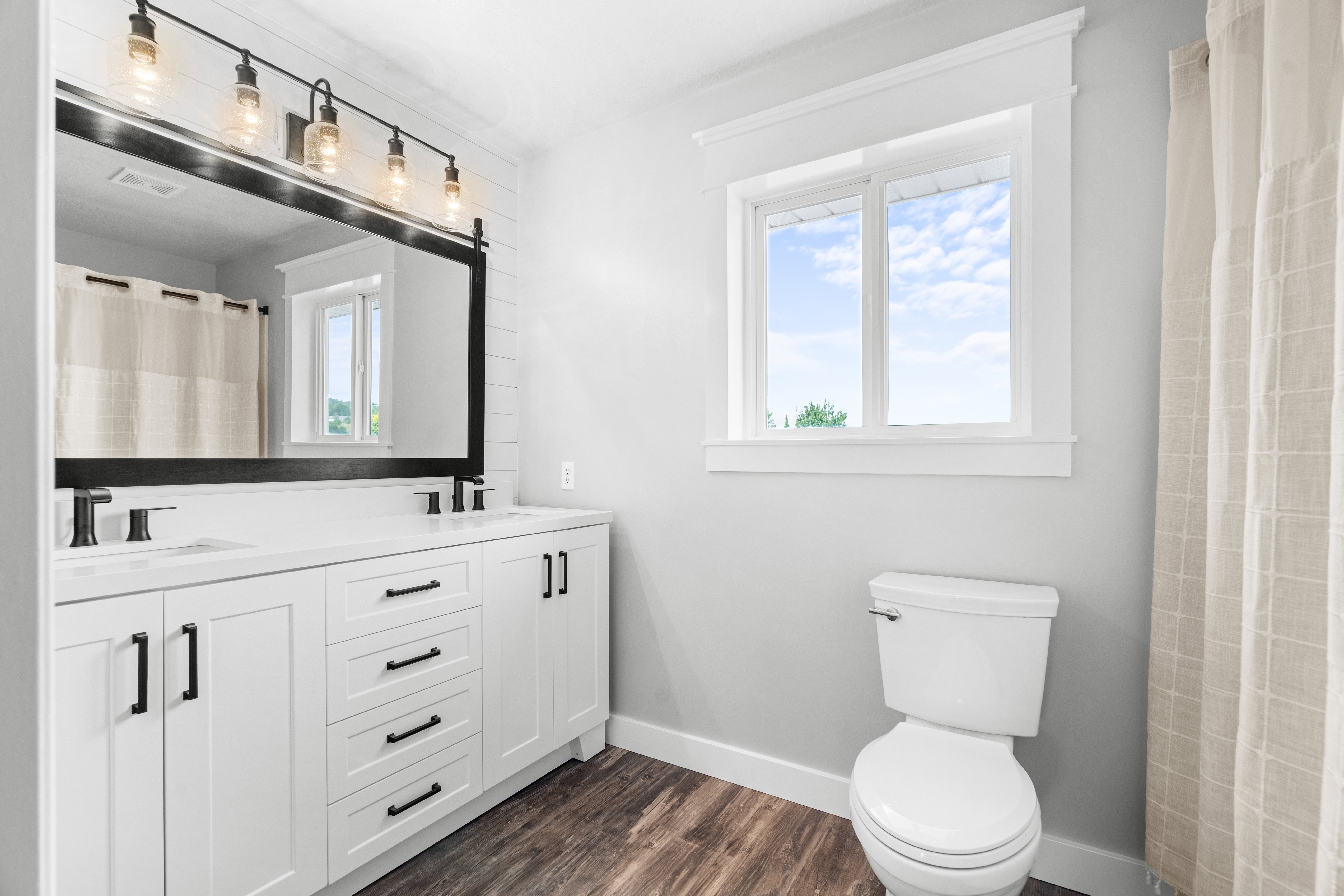 Primary bathroom with dual vanity and white cabinetry and dark hardware, set against a white subway tile backsplash