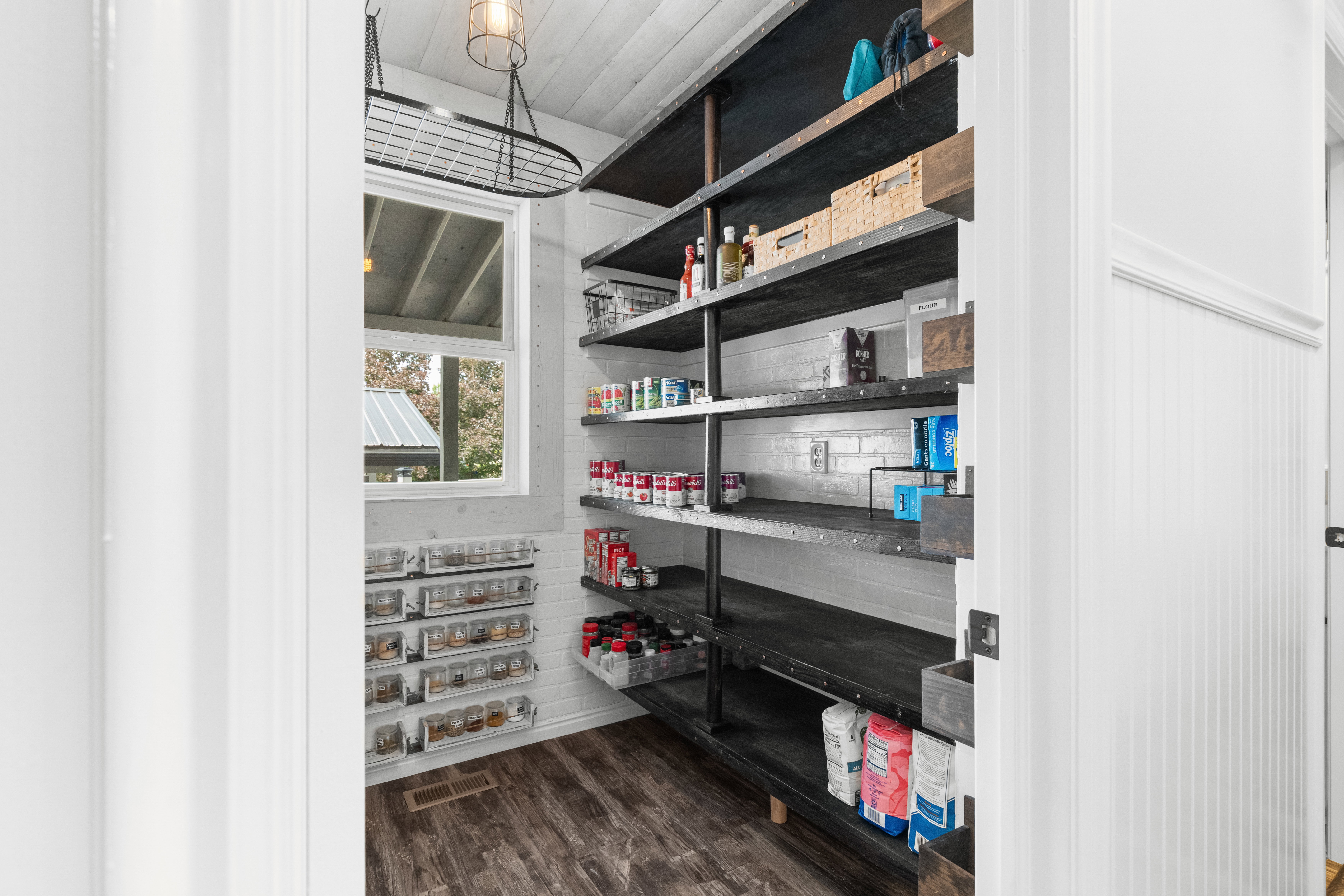 Custom Pantry featuring extensive industrial-style shelving, wood-finish flooring, a white subway tile backsplash, and beadboard paneling