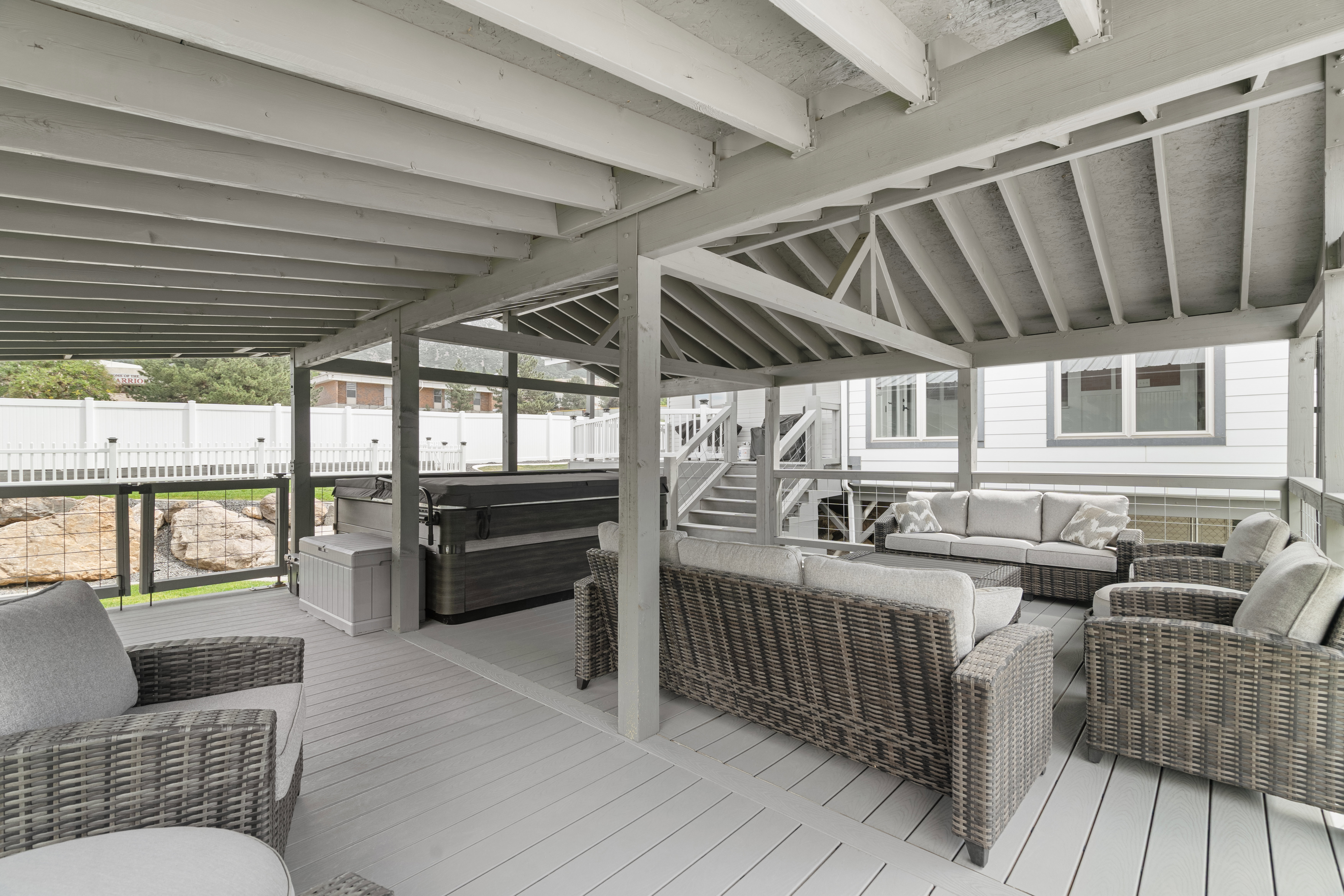 Custom-built covered gazebo deck with quality 6x6 construction, exposed beam ceiling, composite decking, and glass railings. Spacious design offers the perfect setting for outdoor gatherings and hot tub enjoyment