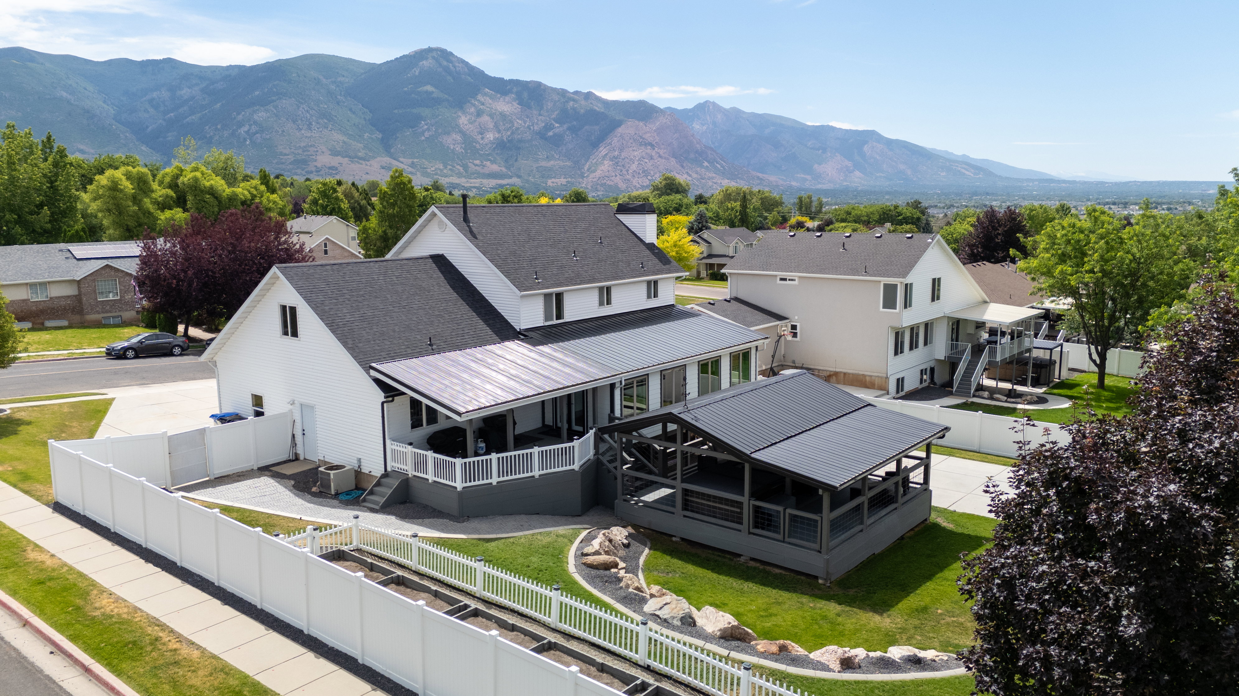 Aerial view of two-story residence featuring a white exterior and dark shingle roof
