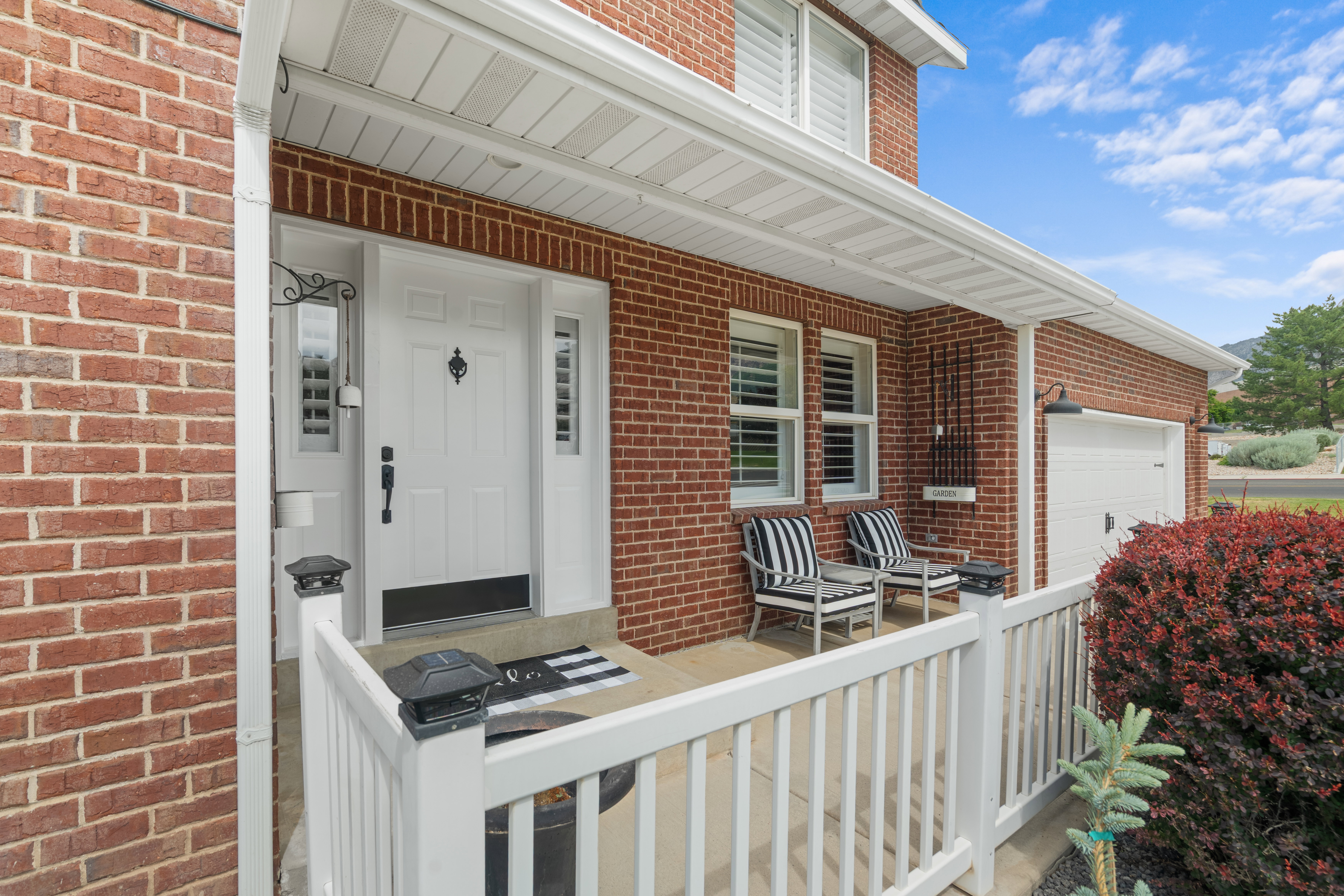 Brick exterior featuring a covered front porch with a white railing