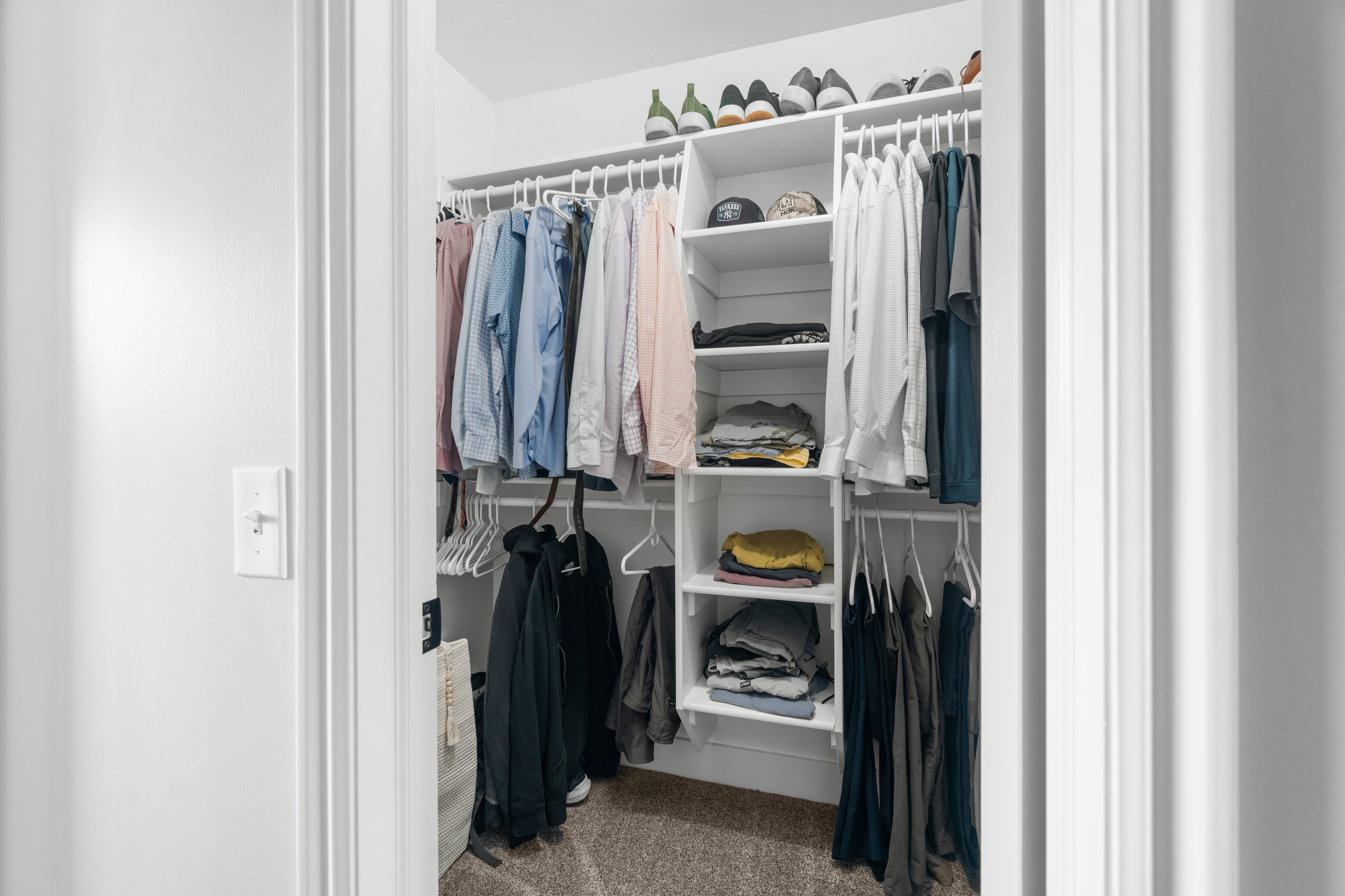 Primary dual walk-in closets featuring built-in shelving, multiple hanging rods, and neutral-toned carpeting