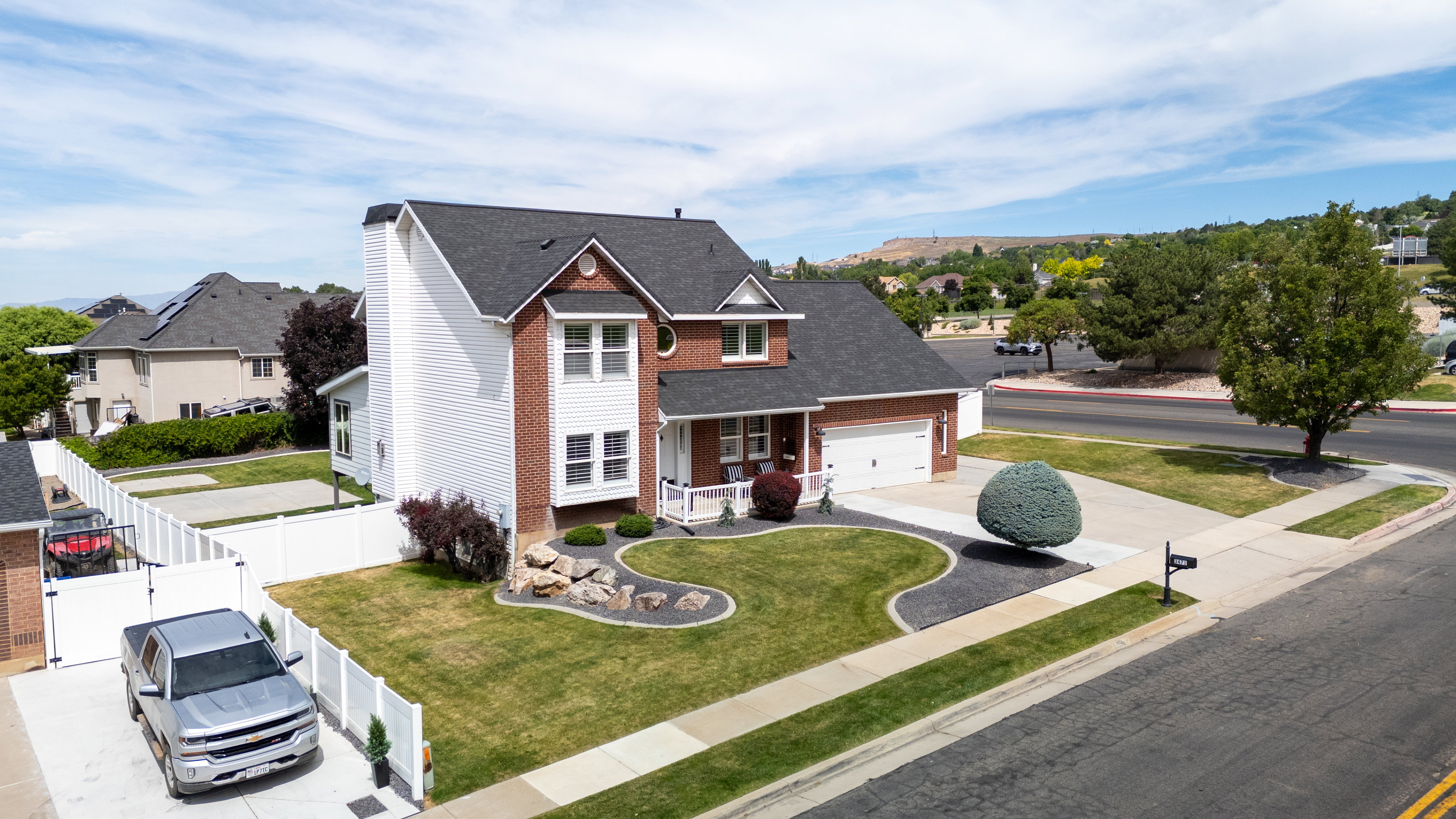 Aerial view of the brick and siding exterior featuring a covered front porch and an attached two-car garage