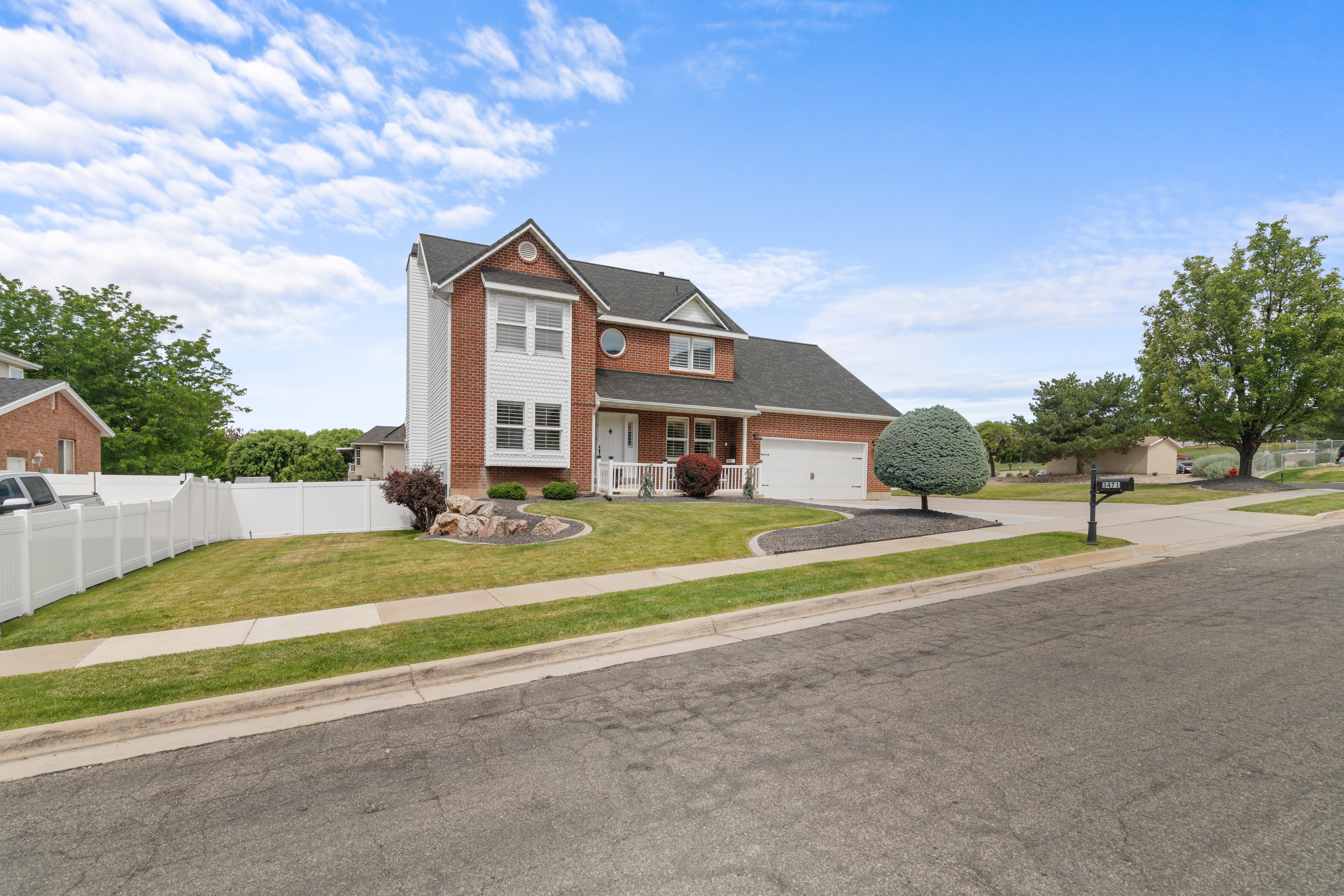 Traditional two-story residence featuring a brick facade with white siding accents and a contrasting dark shingle roof