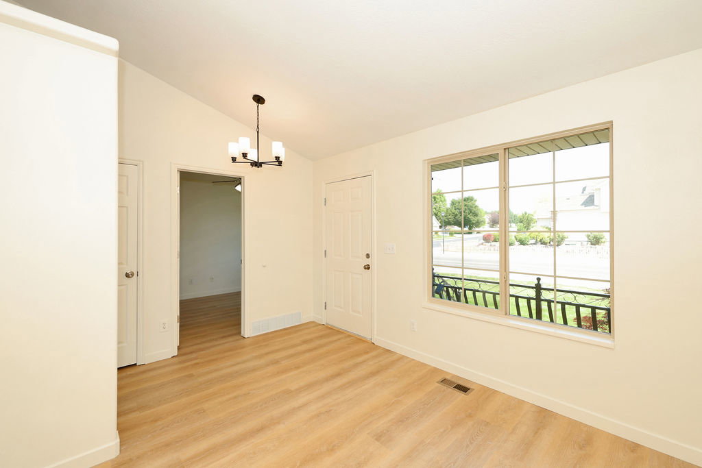 Entry area featuring wood-finish flooring, a contemporary chandelier, and a large window with grilles