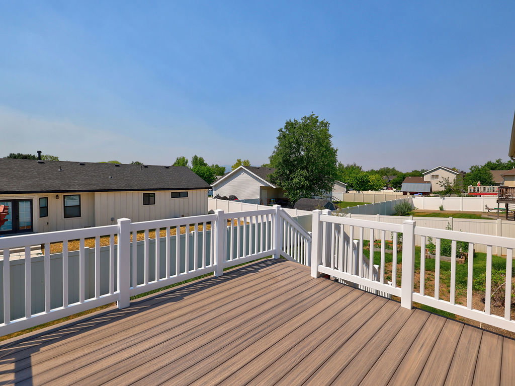 Composite decking with white vinyl railing, offering an elevated perspective of the backyard