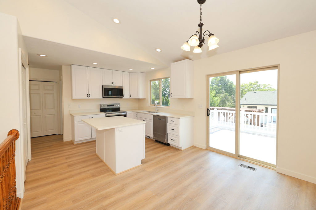Bright kitchen and dining area featuring white cabinetry, stainless steel appliances, and a central island