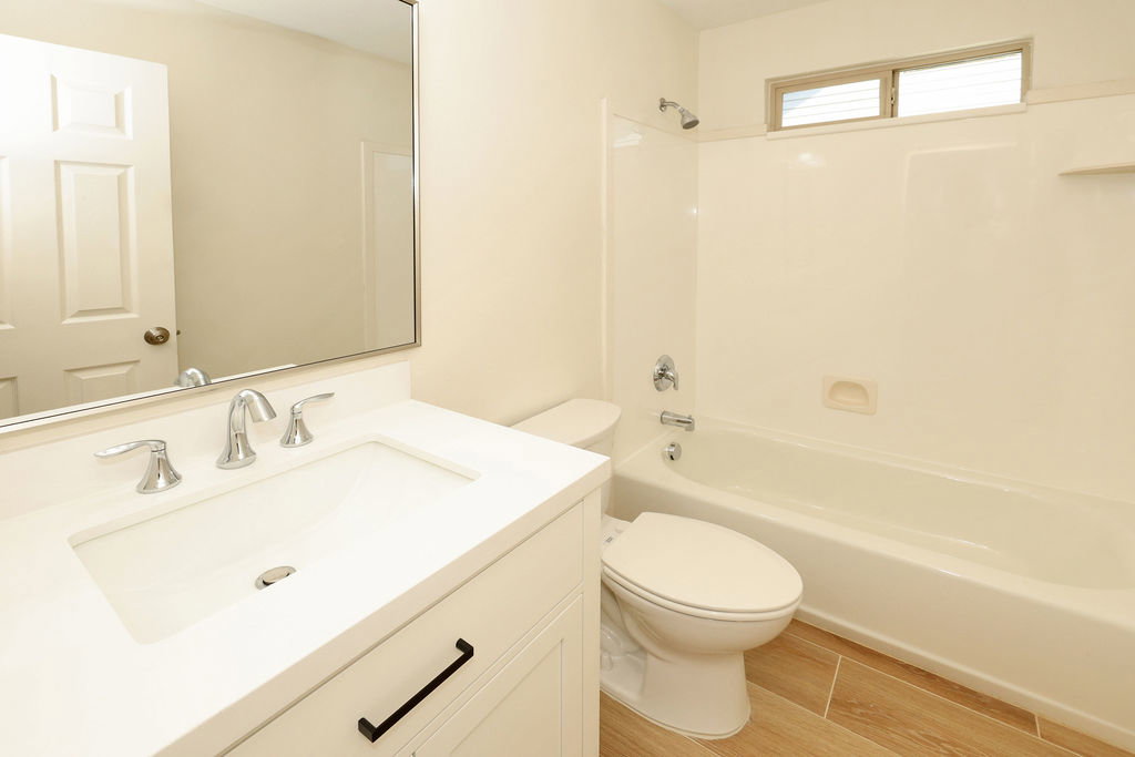 Bathroom featuring a white vanity with an integrated sink, chrome faucet, and rectangular mirror