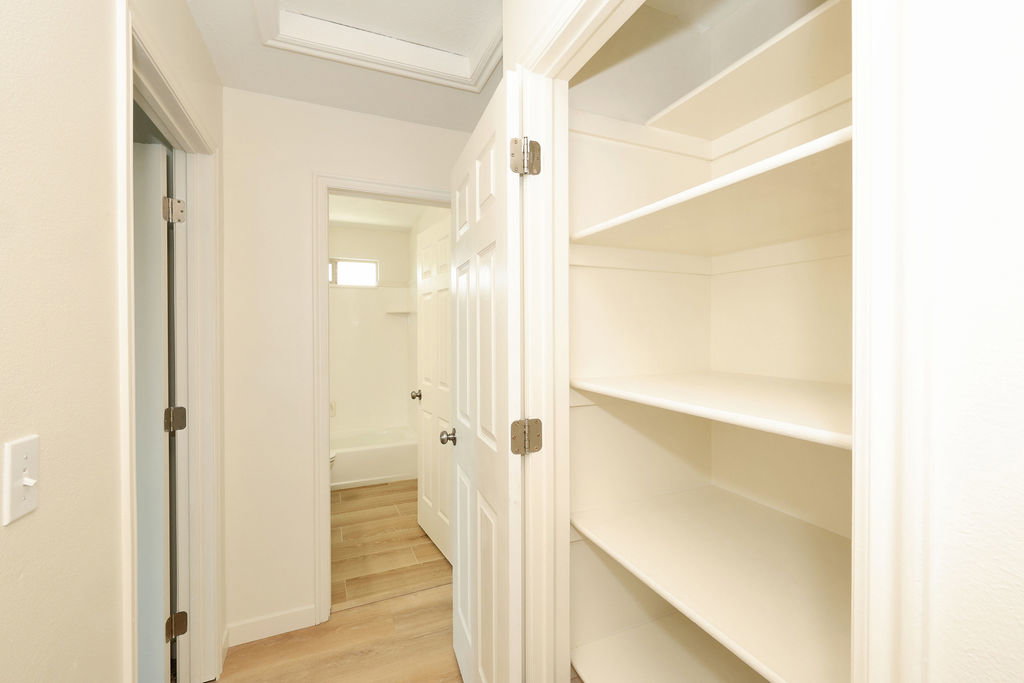 Hallway with integrated shelving unit featuring multiple storage shelves