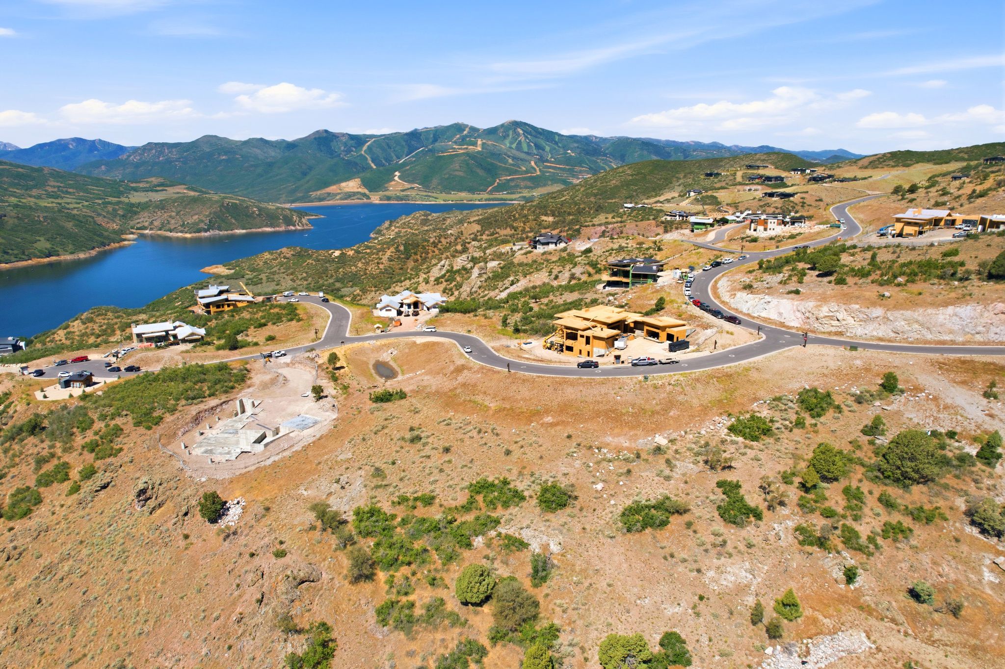 Expansive hillside property featuring a partially excavated building site, surrounded by natural landscaping and paved roadways