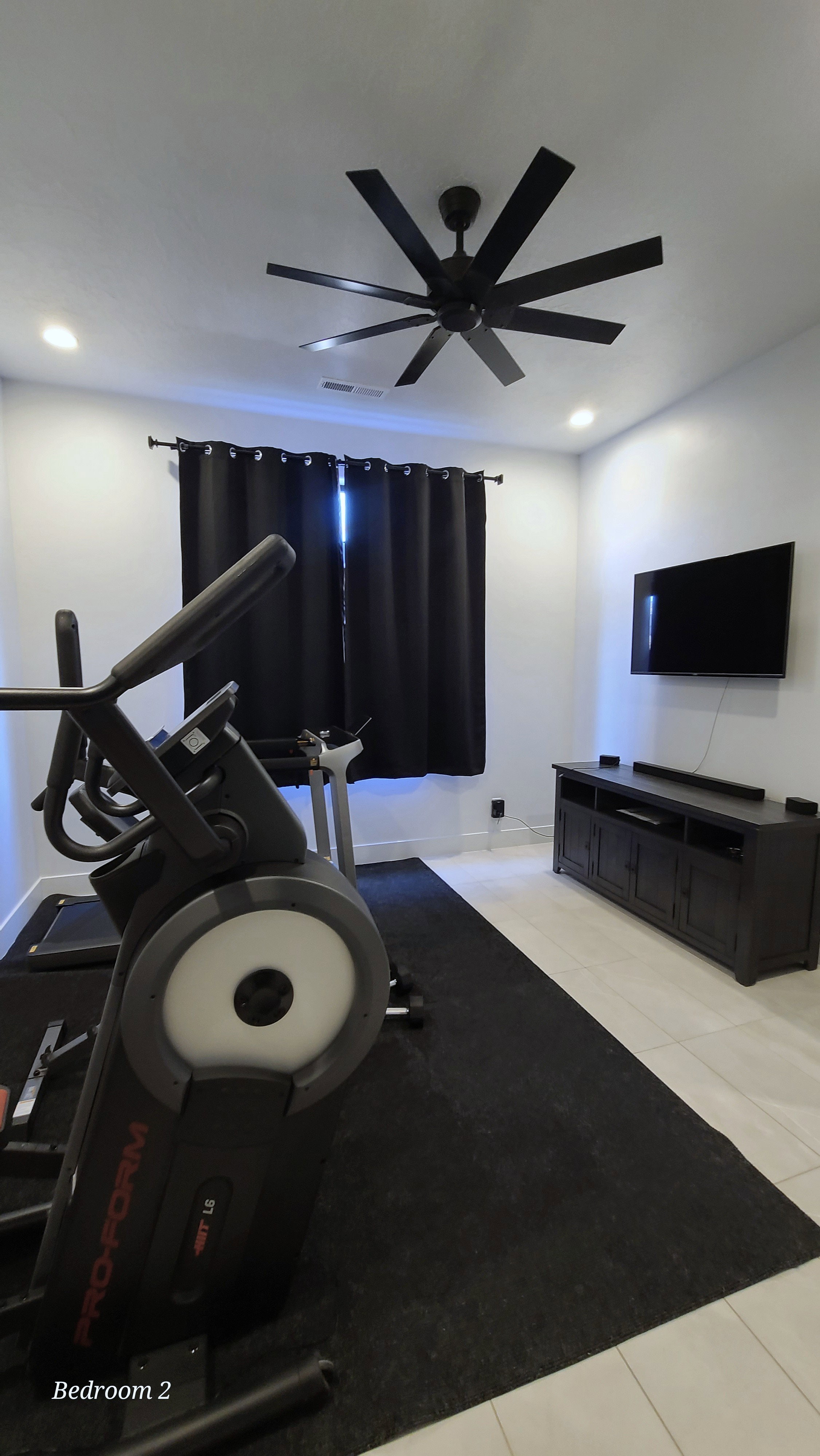 Spacious room featuring a modern black ceiling fan, recessed lighting, and light-toned flooring