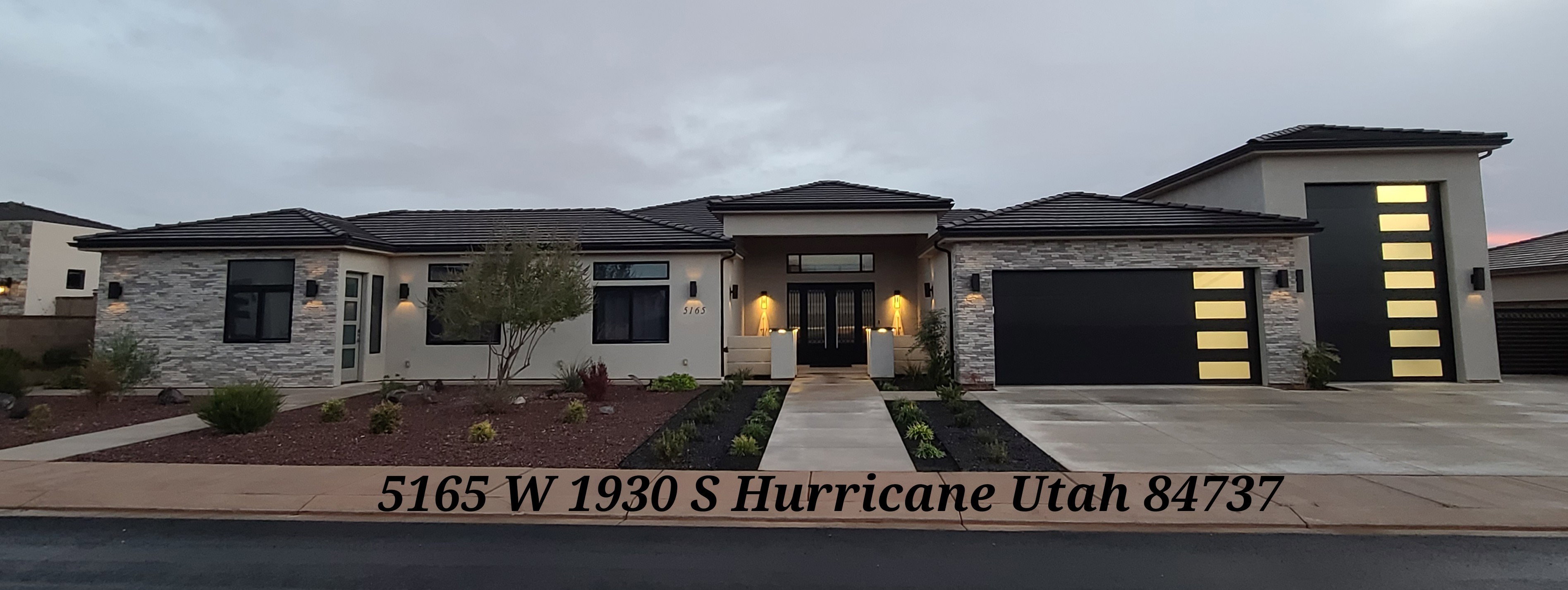 Contemporary exterior featuring a black roofline, stone veneer accents, and a dual-car garage with frosted panel inserts