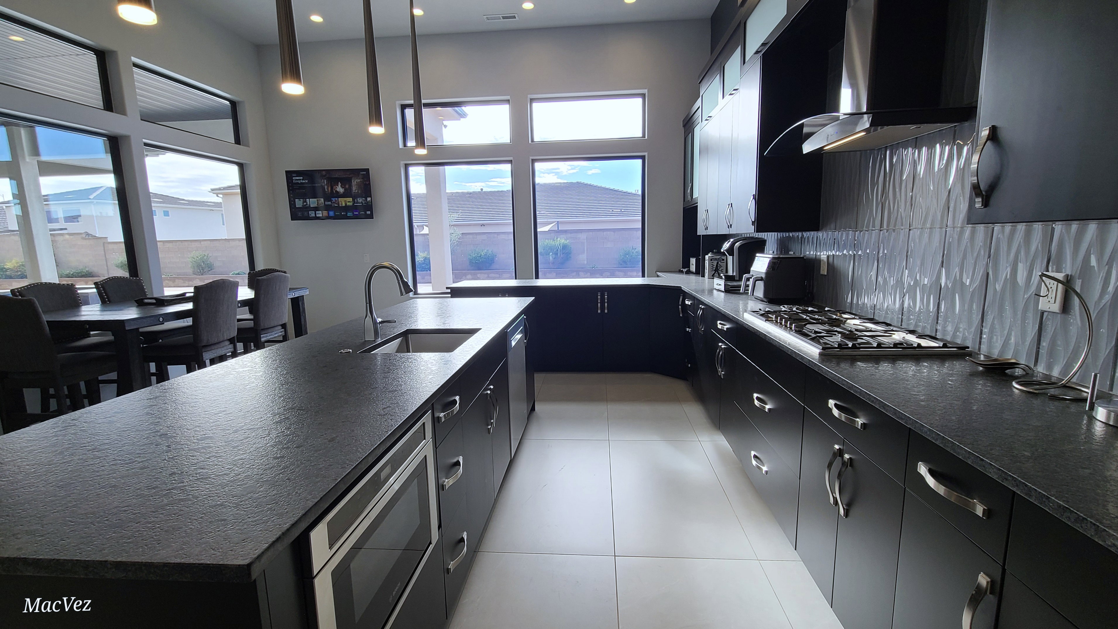 Modern kitchen featuring dark cabinetry, dark textured countertops, stainless steel appliances, and a gas cooktop