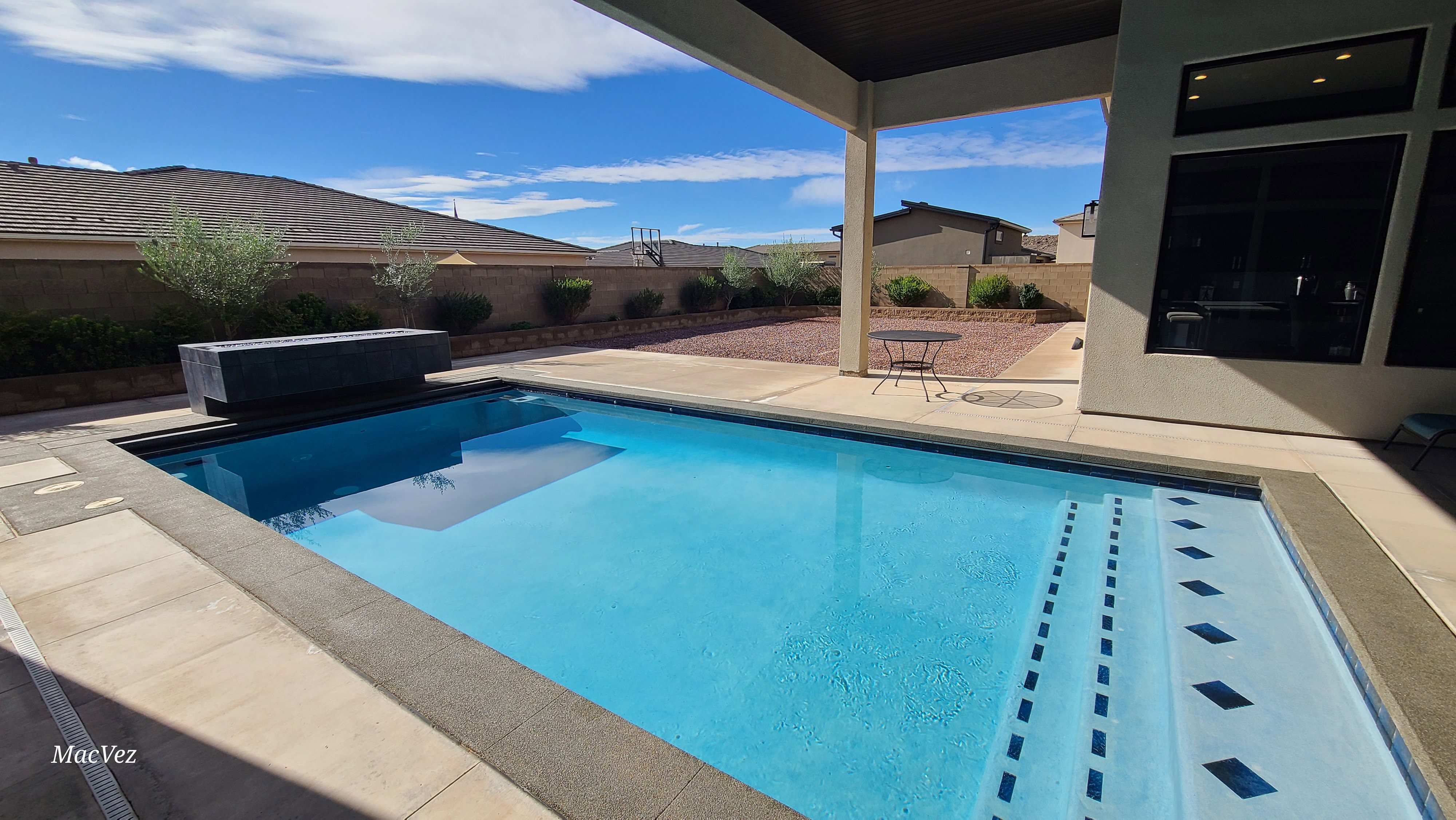 Outdoor swimming pool with integrated steps and a dark-toned water feature