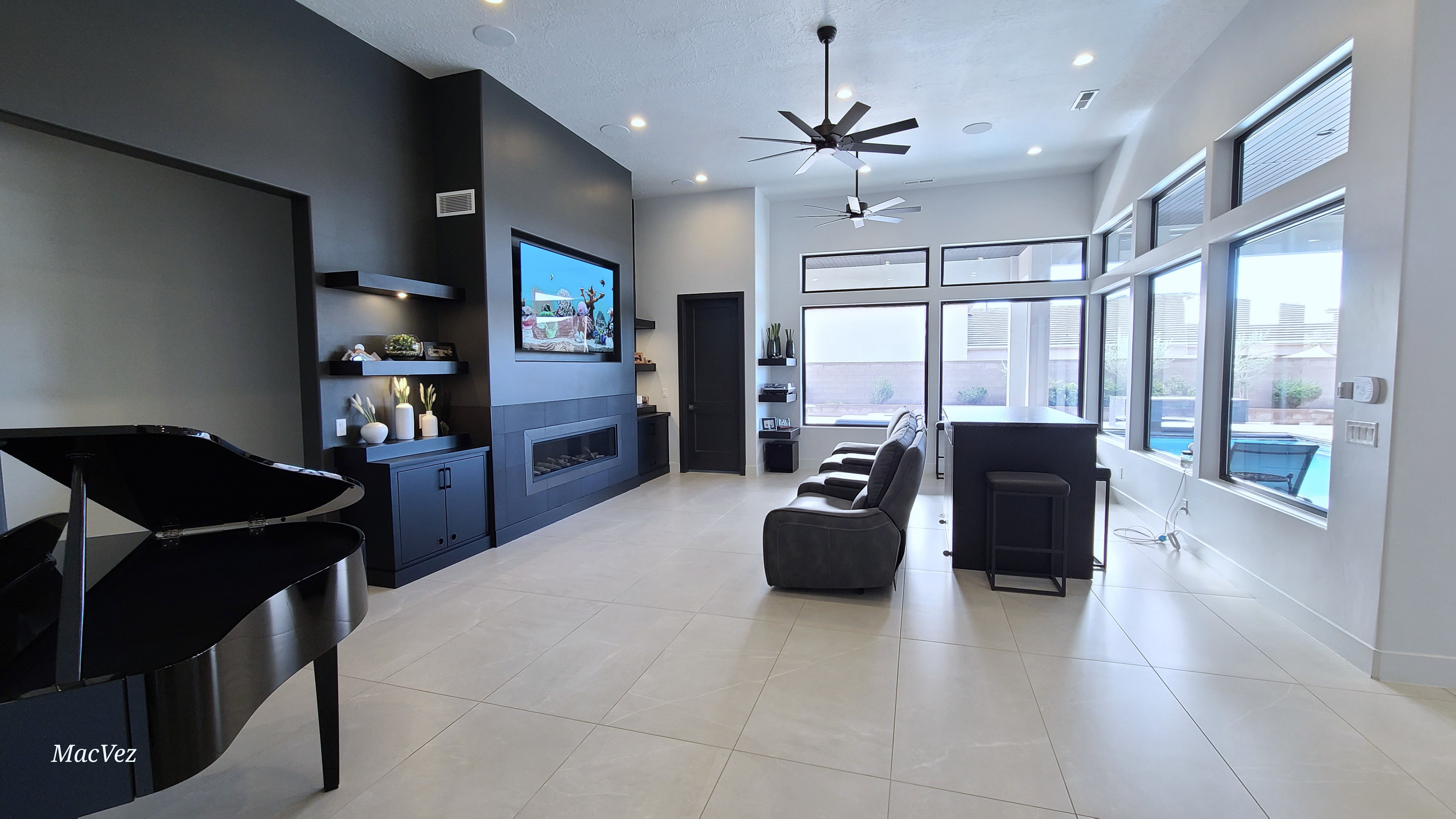 Spacious living area featuring high ceilings, large format tile flooring, a built-in media center with shelving, an integrated fireplace, and expansive windows providing abundant natural light