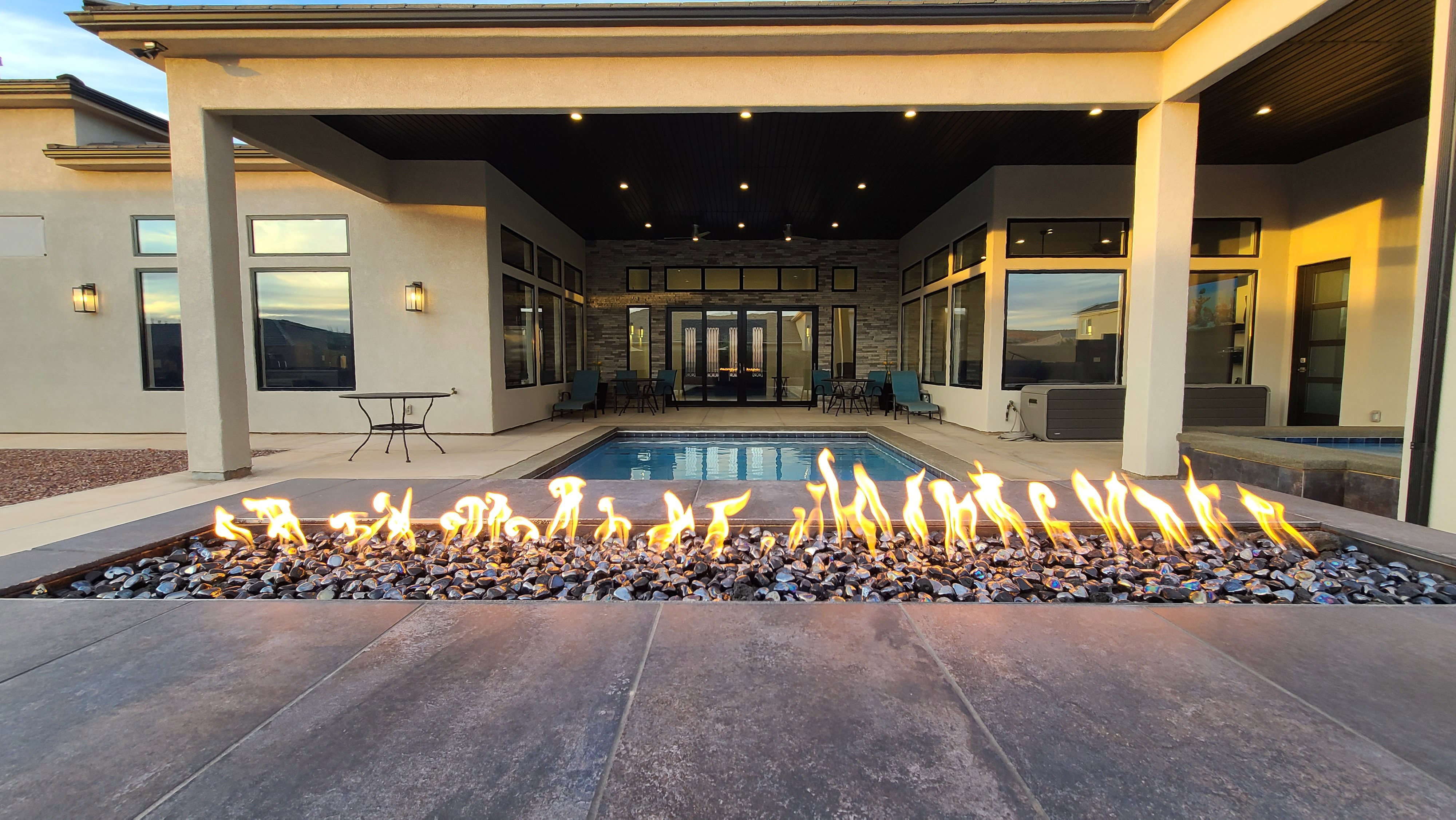 Outdoor fire feature with dark stone accents, bordered by expansive tile patio