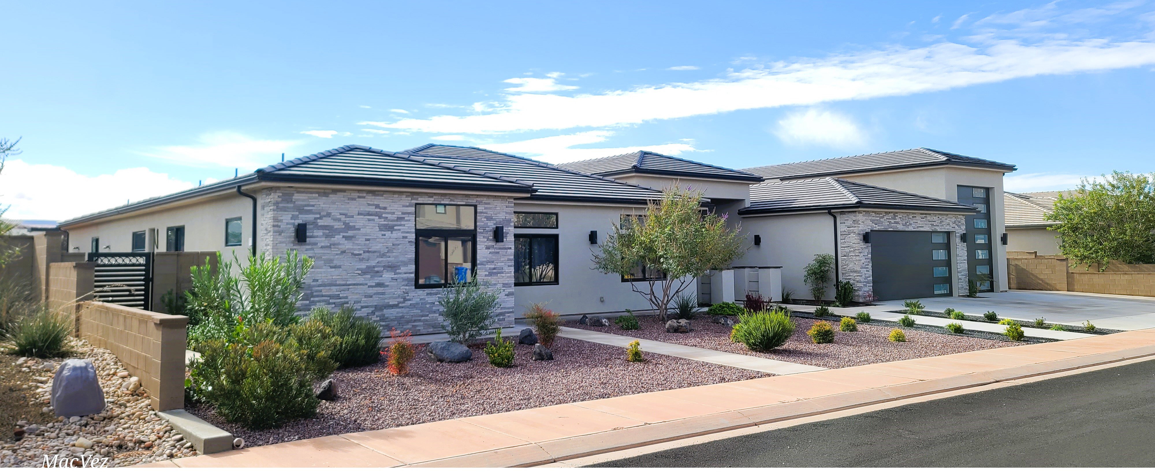 Contemporary facade featuring stone veneer accents, stucco exterior, and a dark tile roof