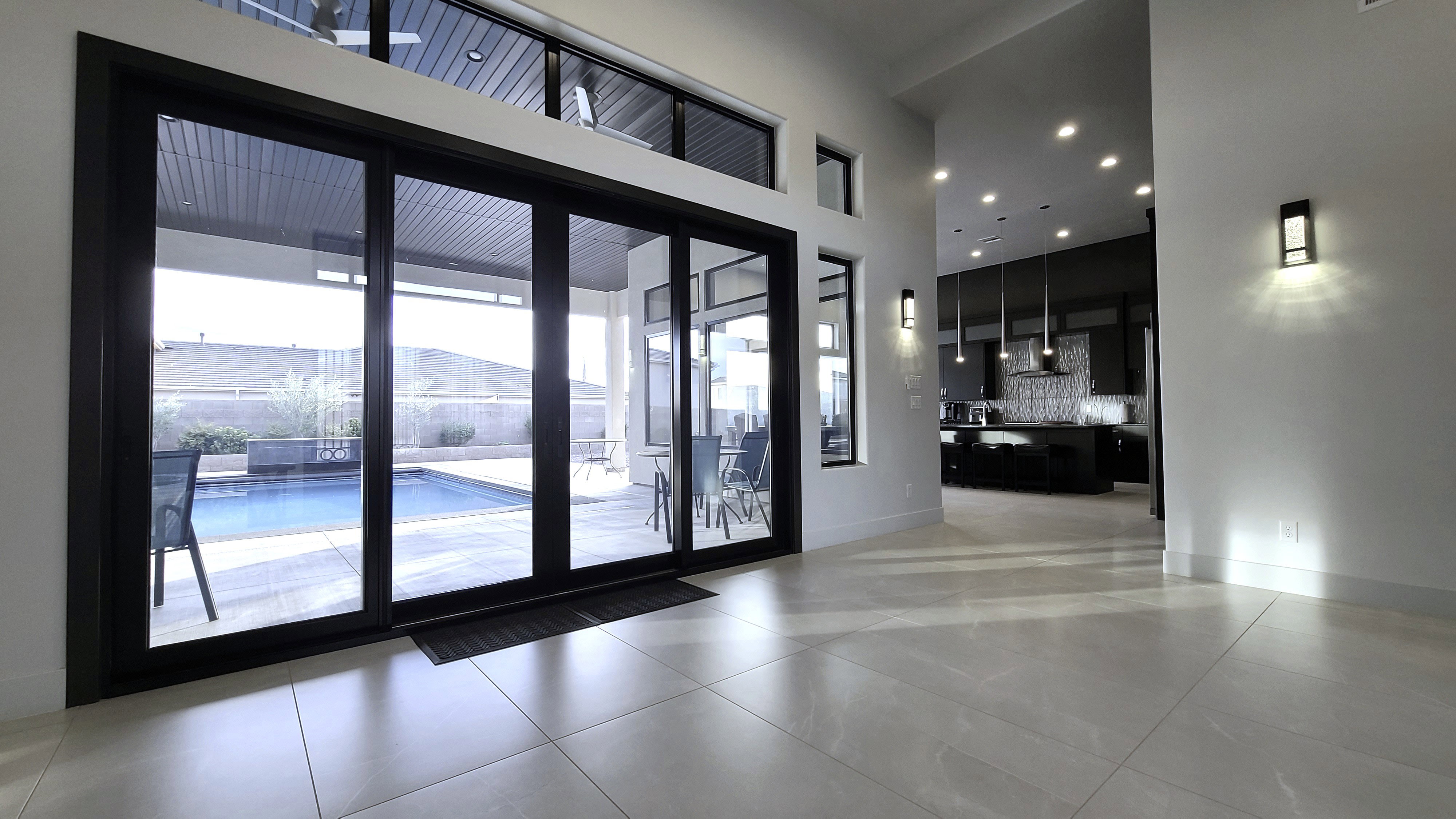 Expansive sliding glass doors opening to a private patio and swimming pool