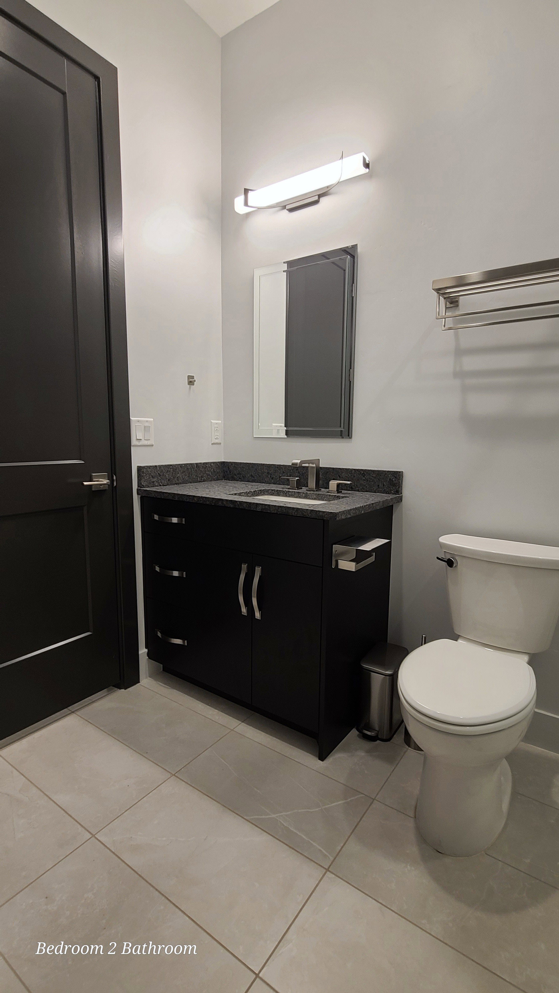 Bathroom vanity with a dark countertop and integrated sink, complemented by a wall-mounted light fixture