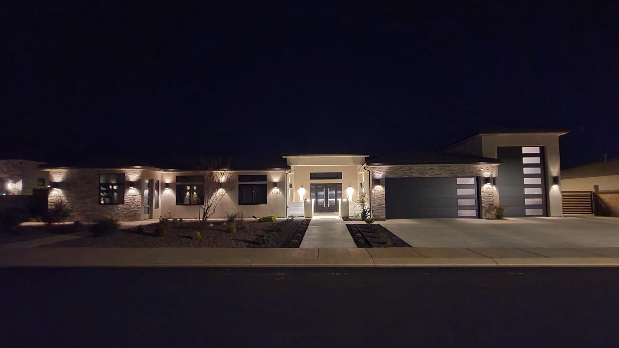 Modern exterior featuring a prominent two-car garage, stone and stucco facade, and an inviting walkway leading to the double front doors