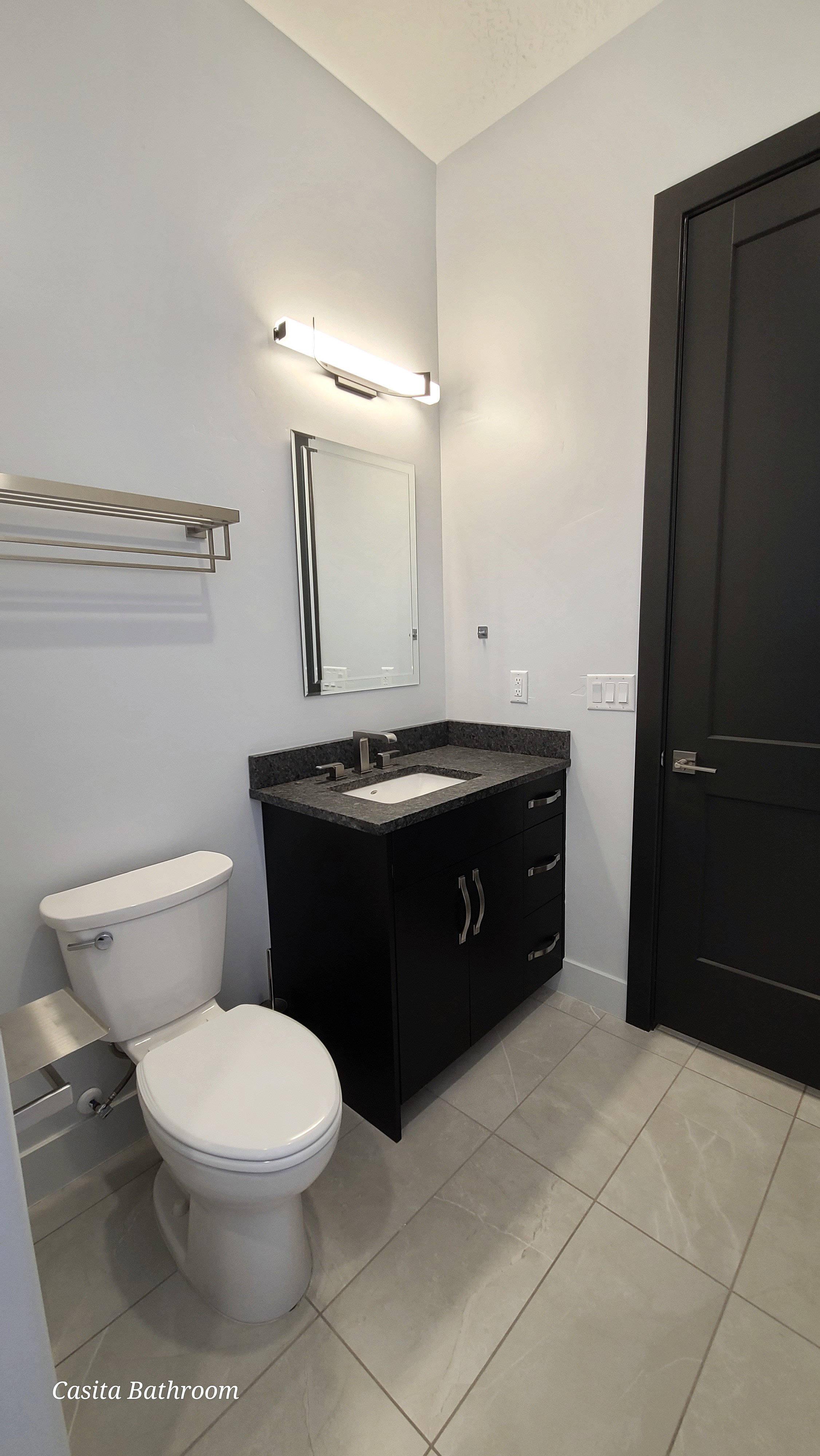 Bathroom featuring a dark wood-finish vanity with a stone countertop, an undermount sink, and a rectangular mirror