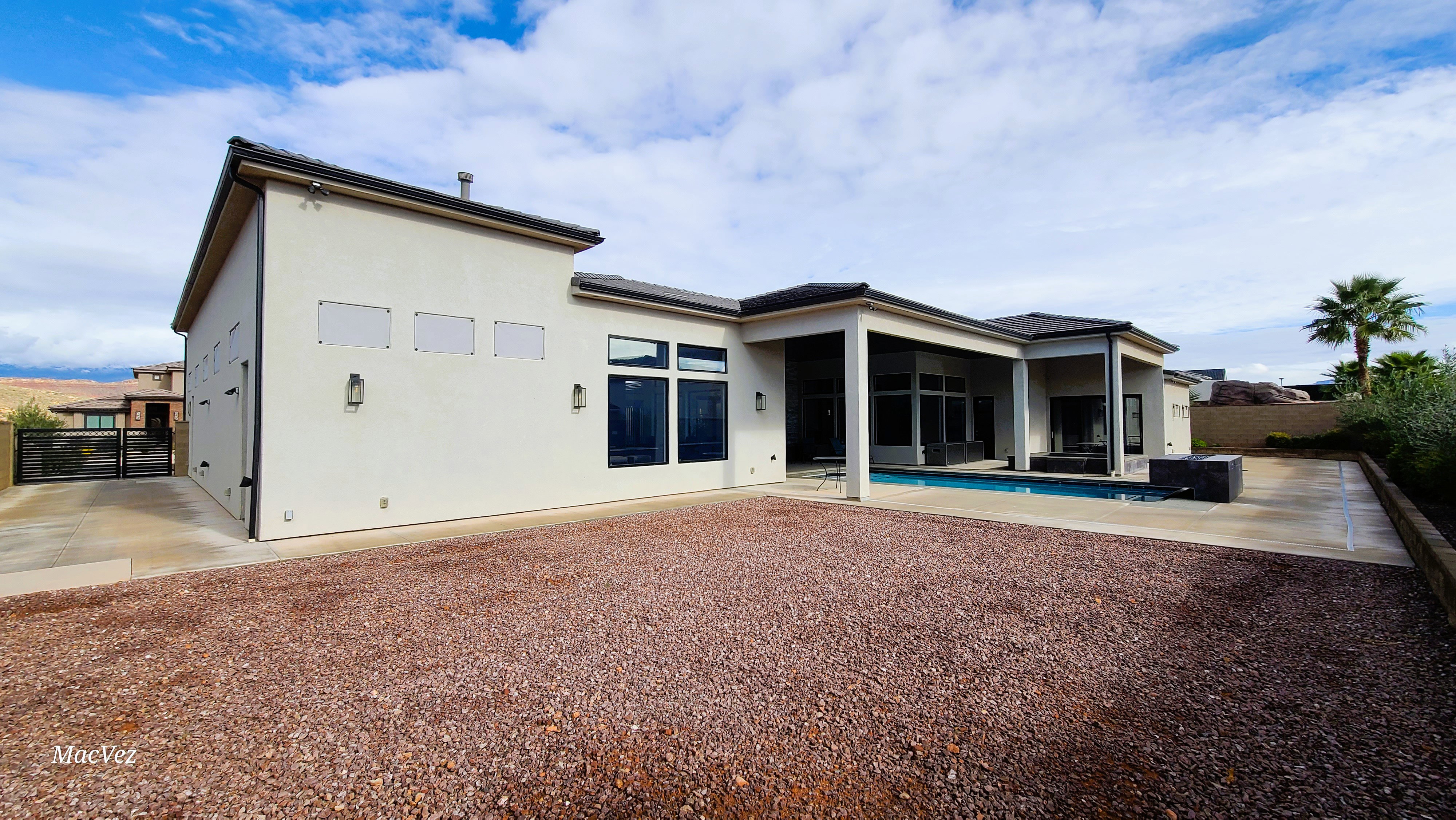 Modern stucco exterior with a flat roofline, dark-framed windows, and an integrated swimming pool