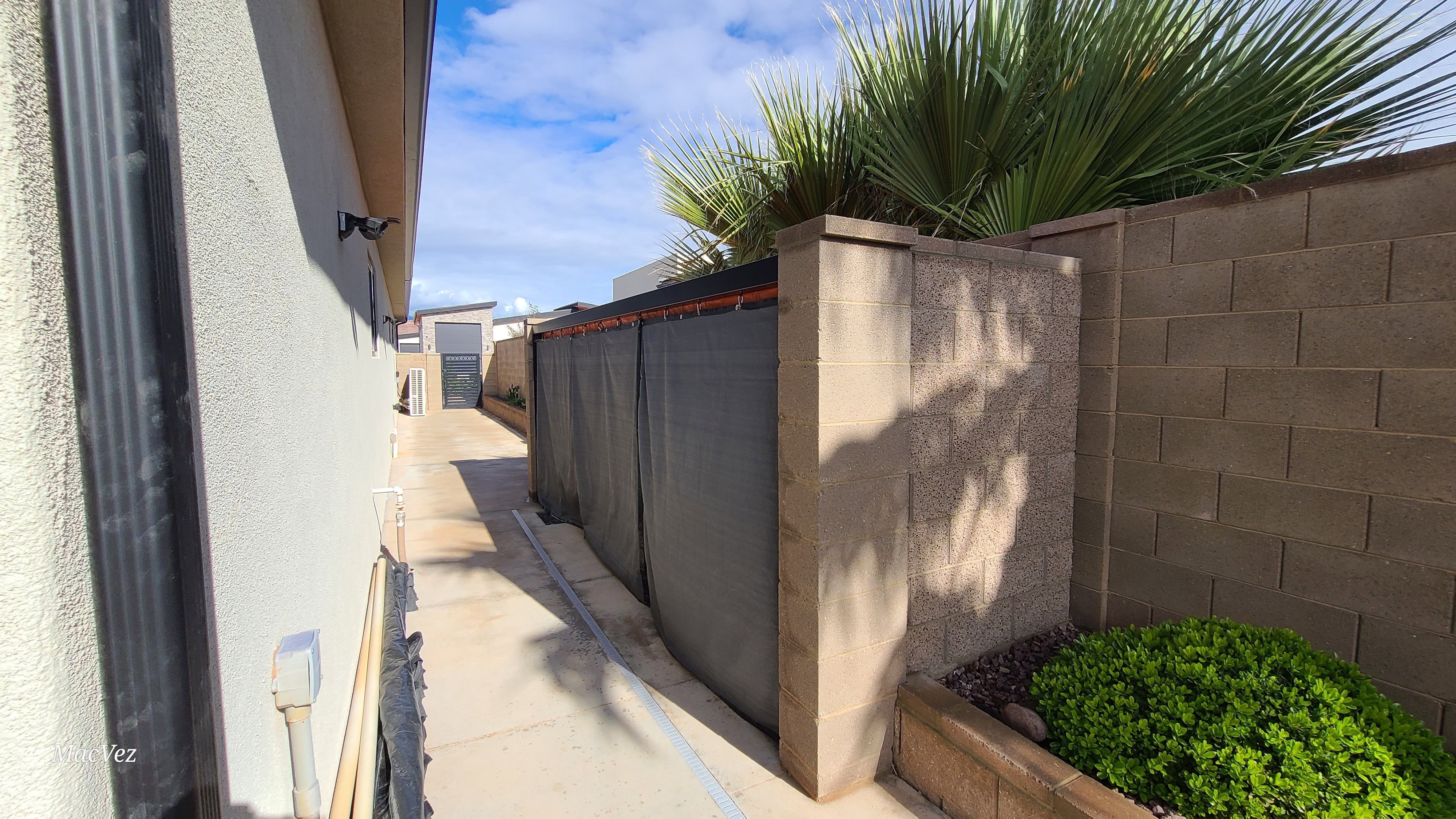 Paved side yard with privacy fencing and a dedicated planter featuring mature landscaping