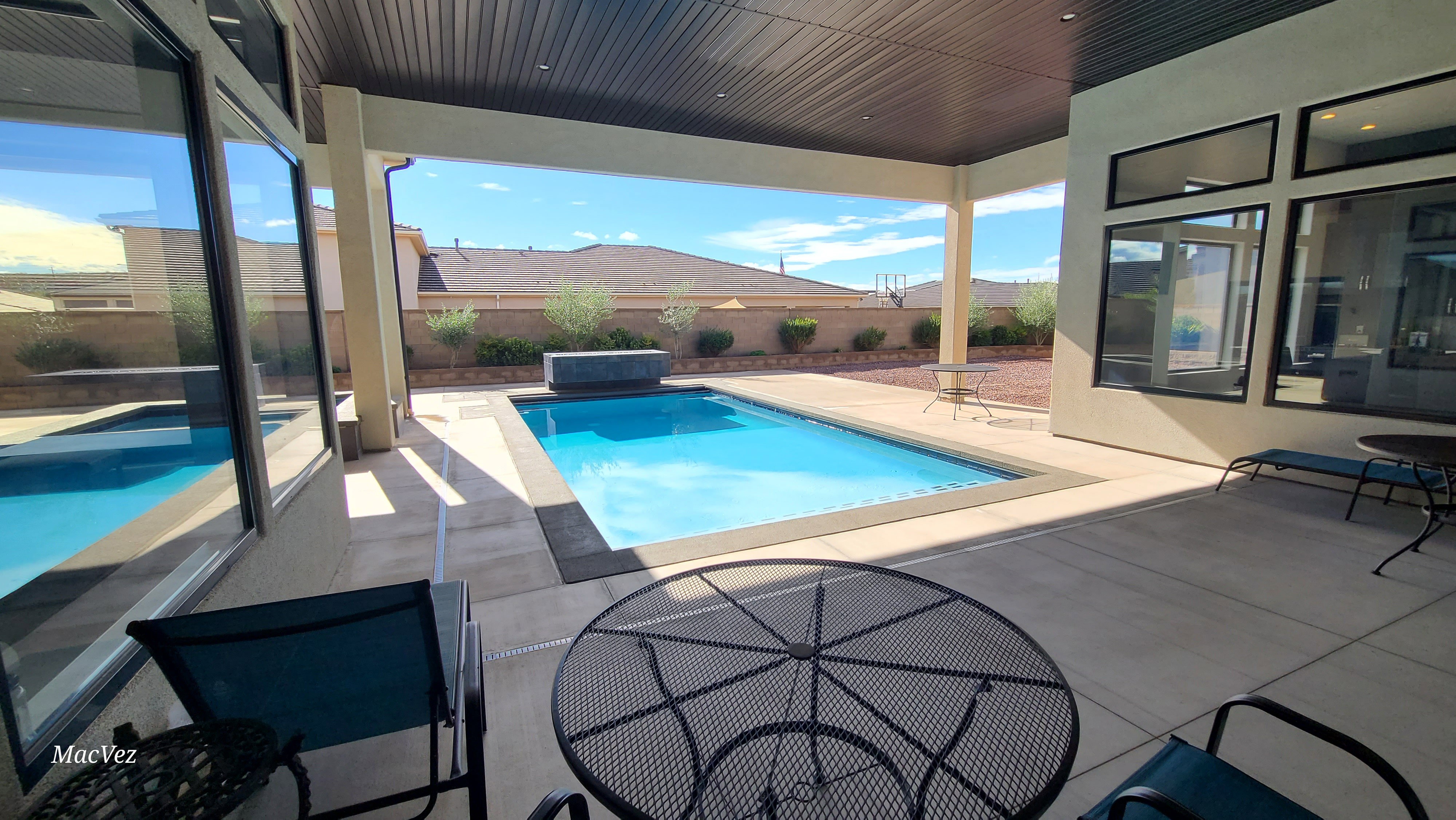 Outdoor living area featuring a covered patio, an in-ground swimming pool, an integrated spa, and expansive glass sliding doors