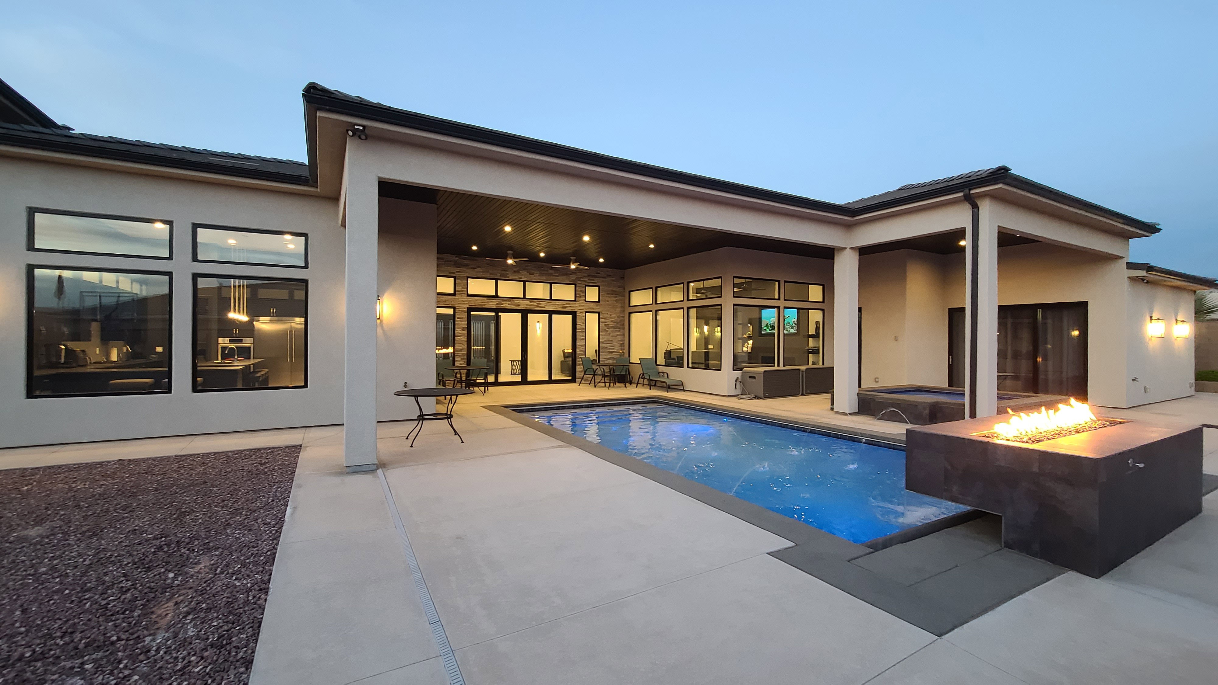 Contemporary stucco exterior with a rectangular swimming pool, integrated spa, and a modern fire pit