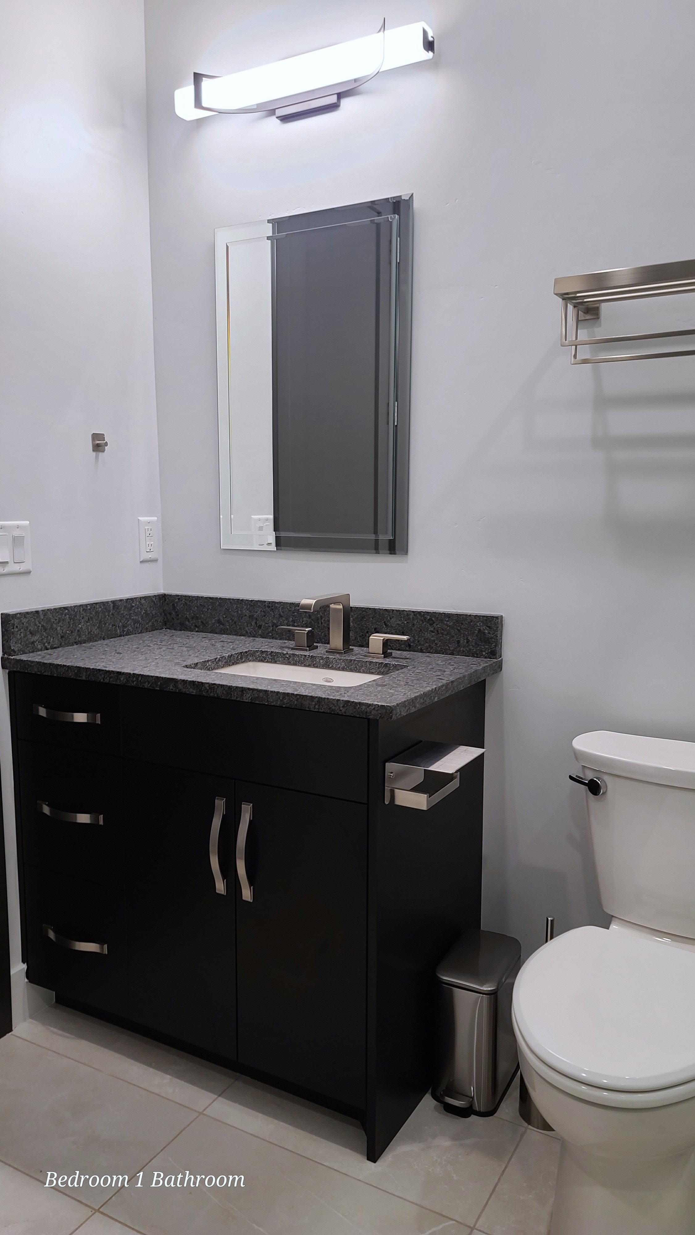 Bathroom vanity with a dark wood-finish cabinet, a gray speckled countertop, and an undermount sink