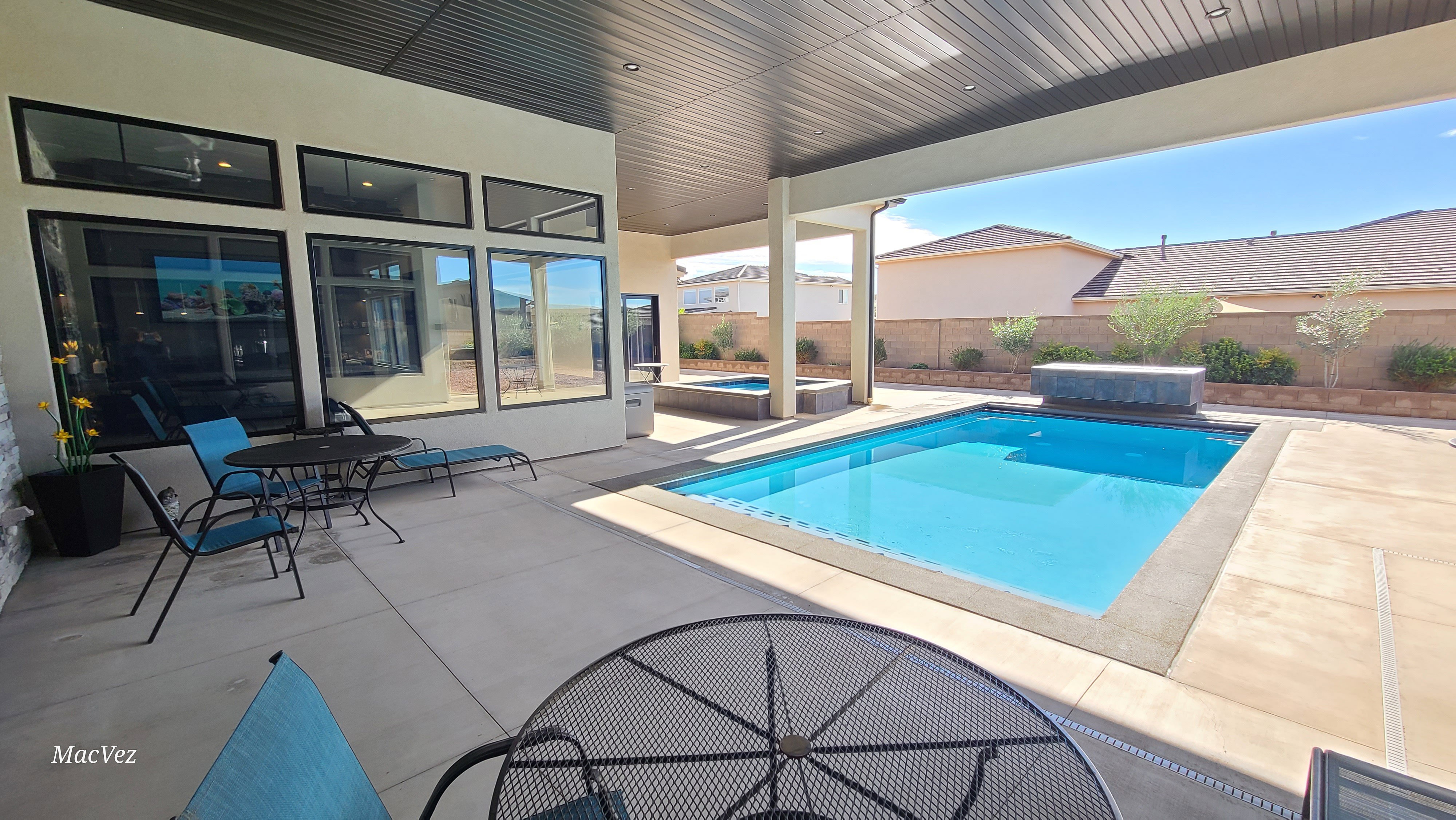 Covered patio with a rectangular swimming pool, integrated spa, and concrete decking