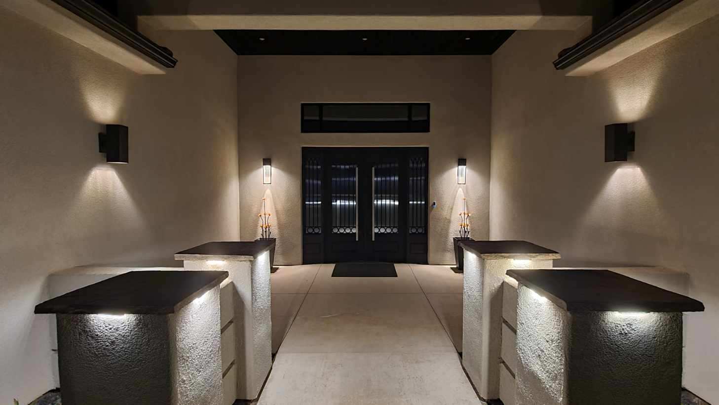 Contemporary entryway featuring double dark-paneled doors with frosted glass, flanked by vertical sconces