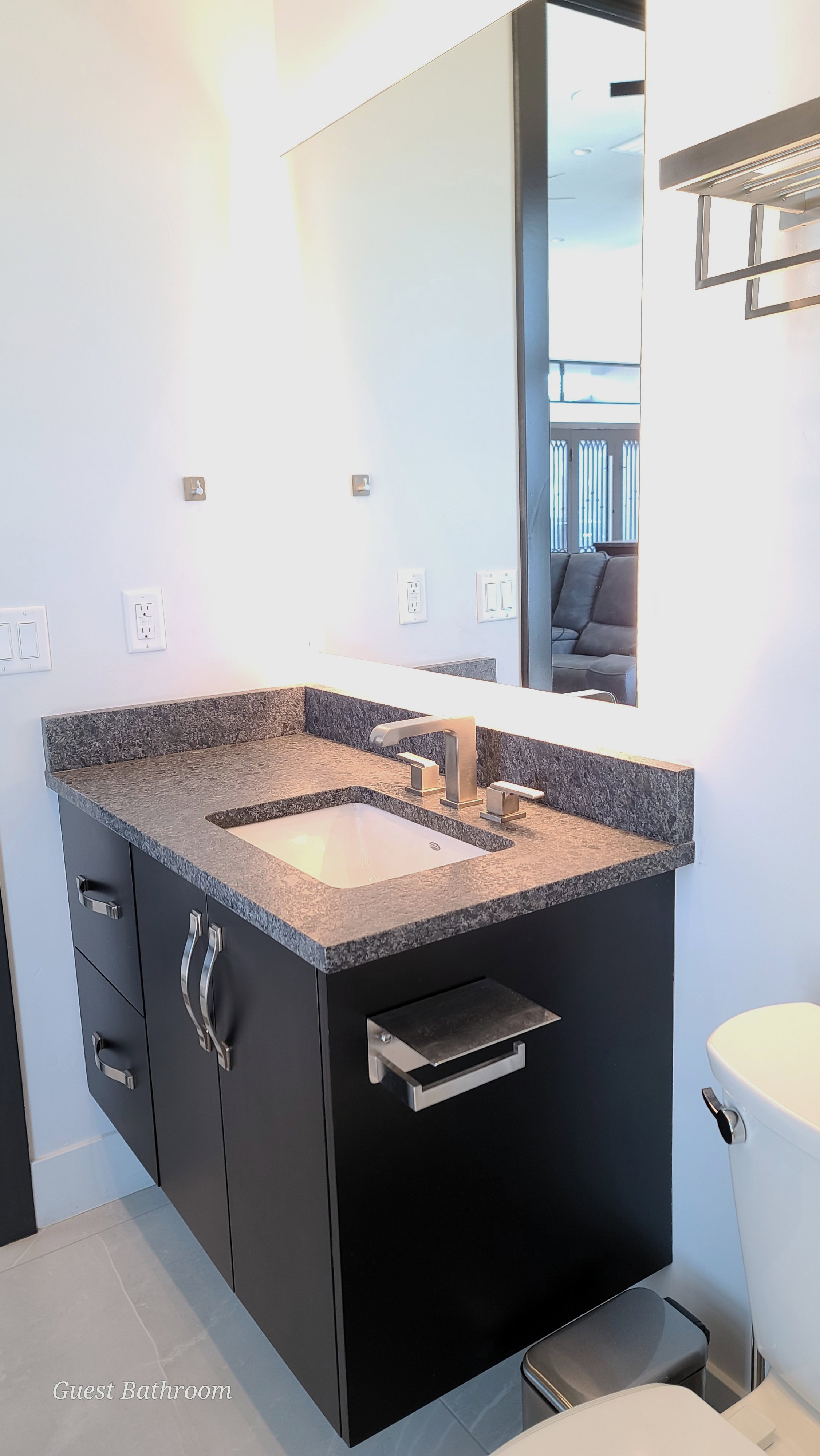 Floating vanity with a built-in sink, dark countertop, and brushed nickel fixtures