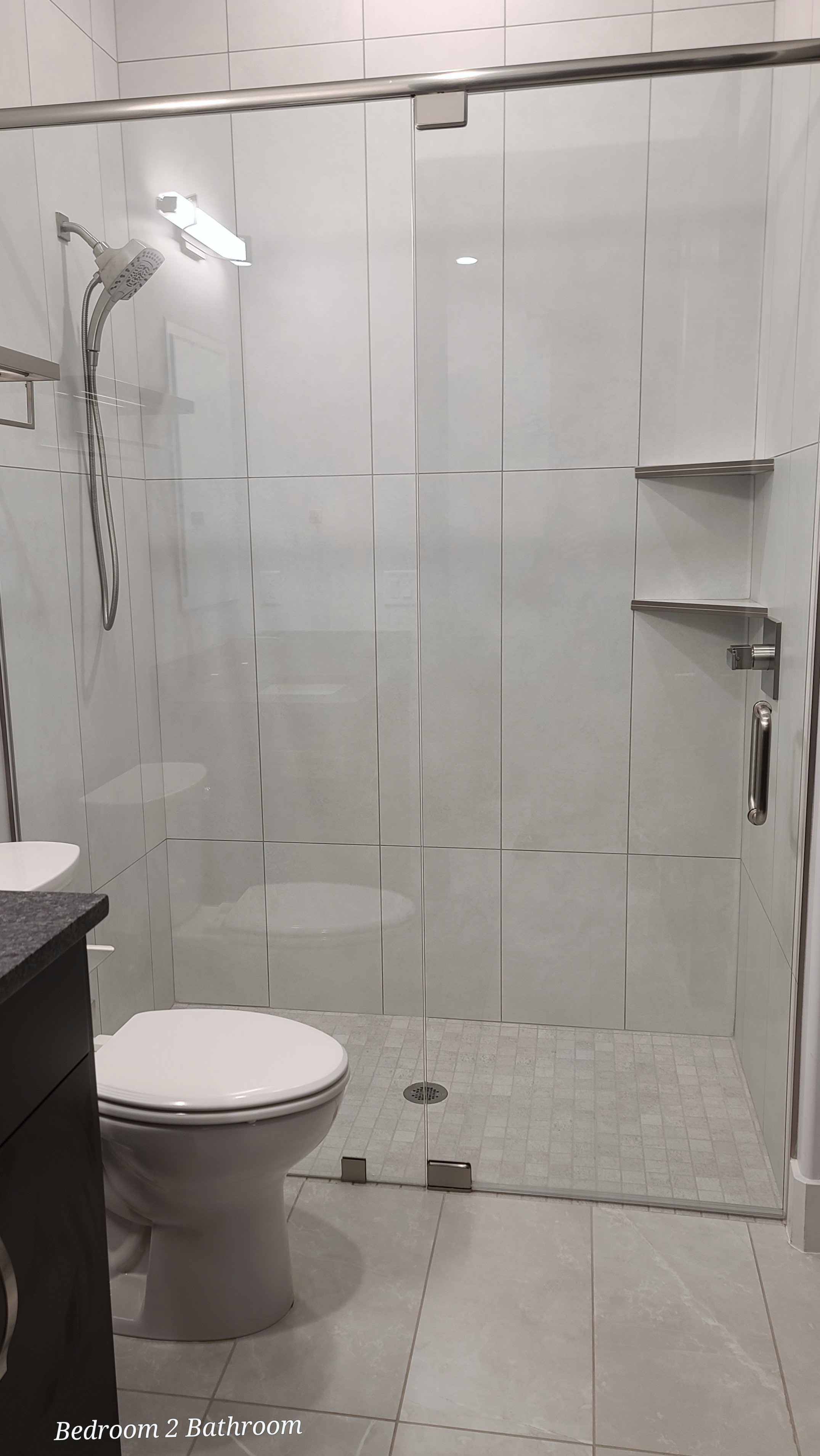 Glass-enclosed shower featuring white subway tile walls, a mosaic tile shower pan, and a handheld shower head