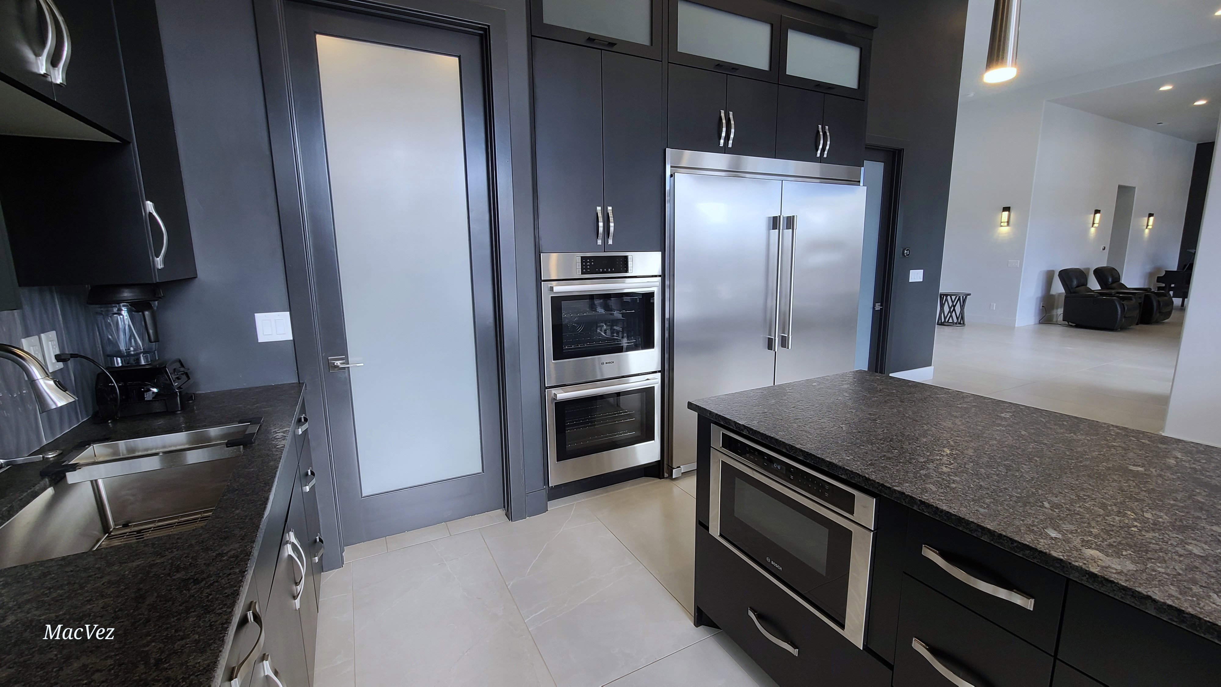 Kitchen featuring dark cabinetry, stainless steel appliances, a double oven, and an integrated microwave within the island