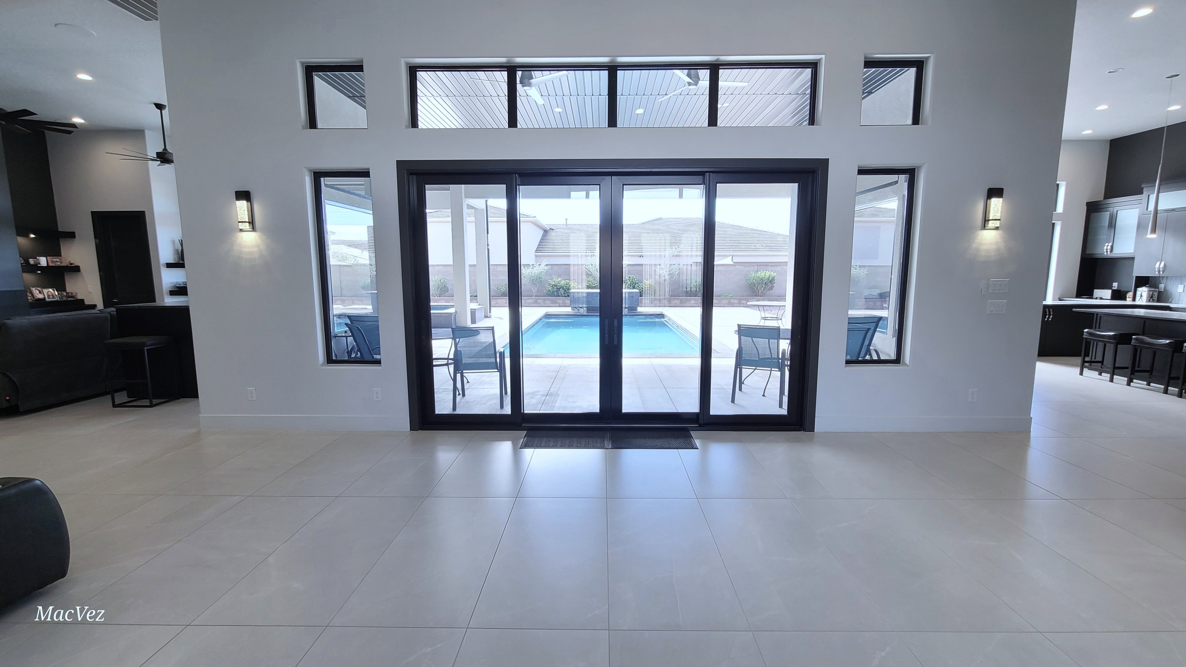 Expansive glass sliding doors open to a backyard with a swimming pool