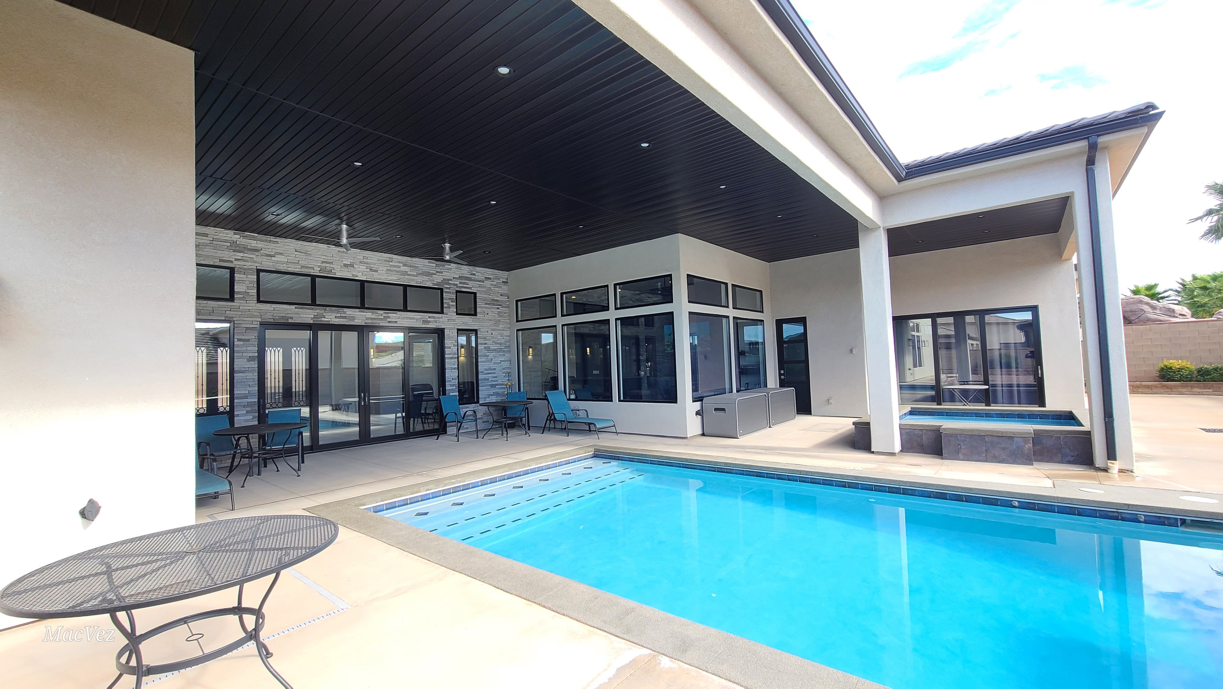 Outdoor swimming pool with integrated spa, bordered by a substantial concrete patio