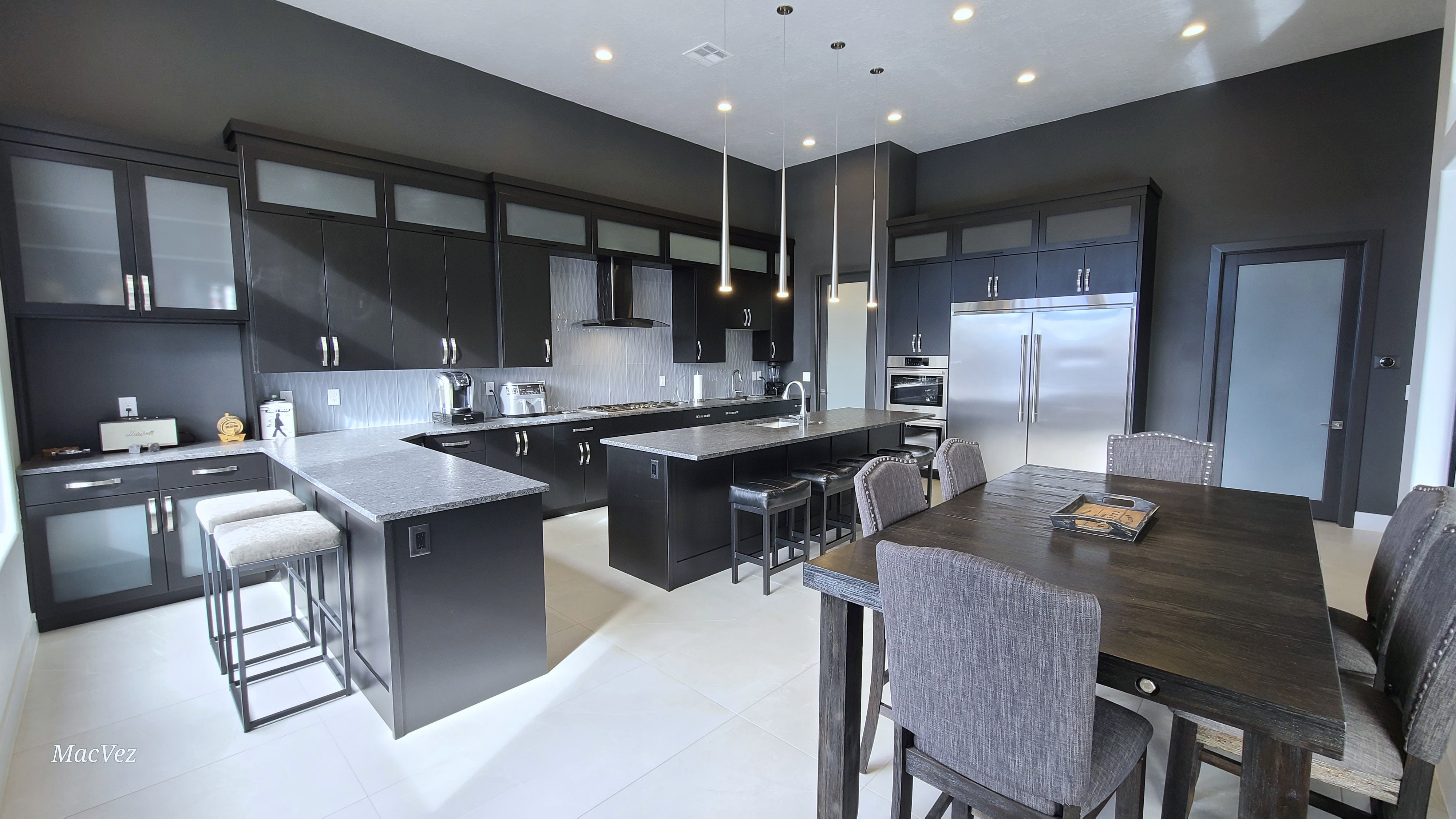 Spacious kitchen featuring dark cabinetry with frosted glass accents, light-toned tile flooring, and integrated stainless steel appliances