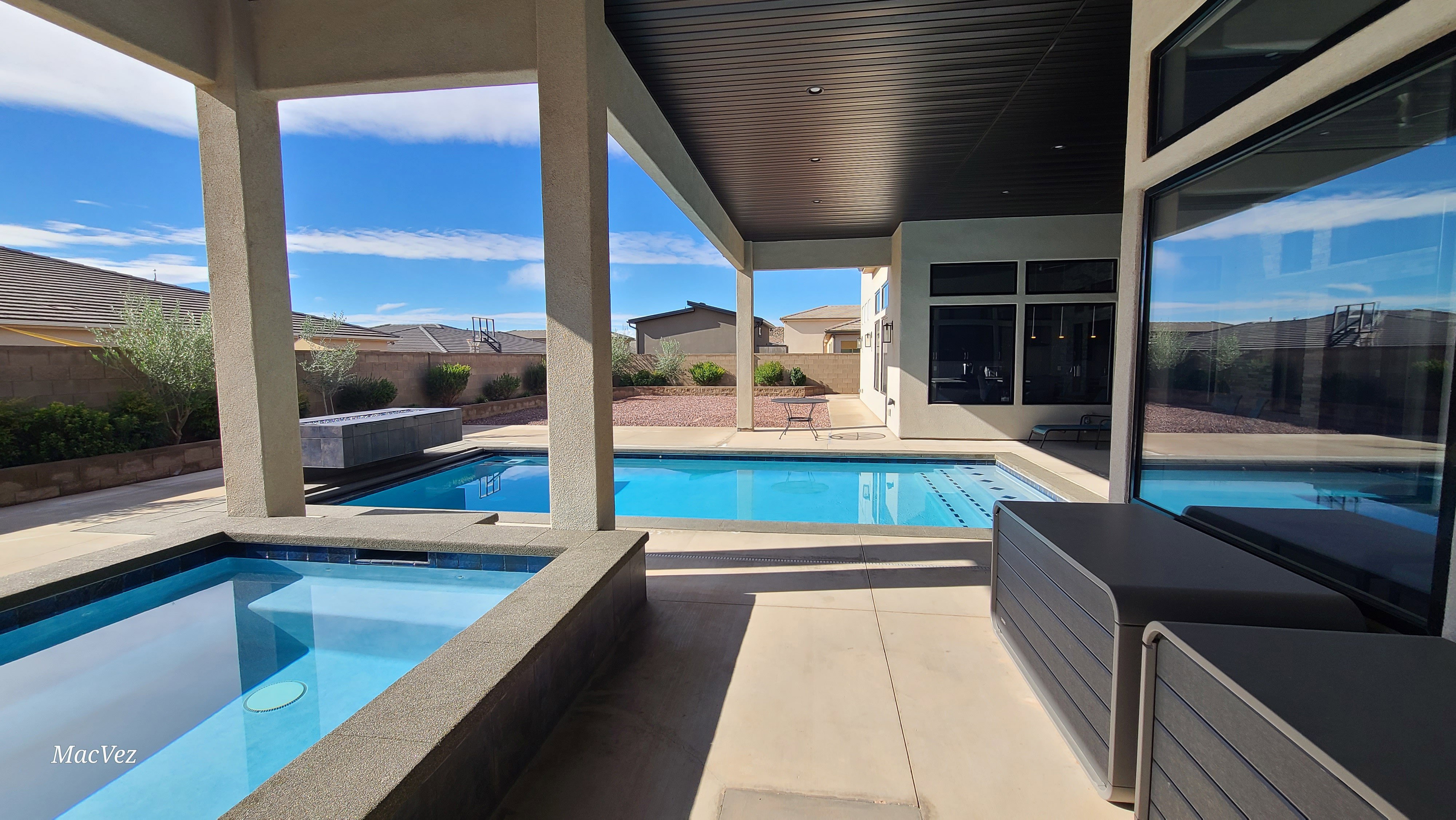 Expansive outdoor living area featuring a covered patio, integrated pool, and separate spa