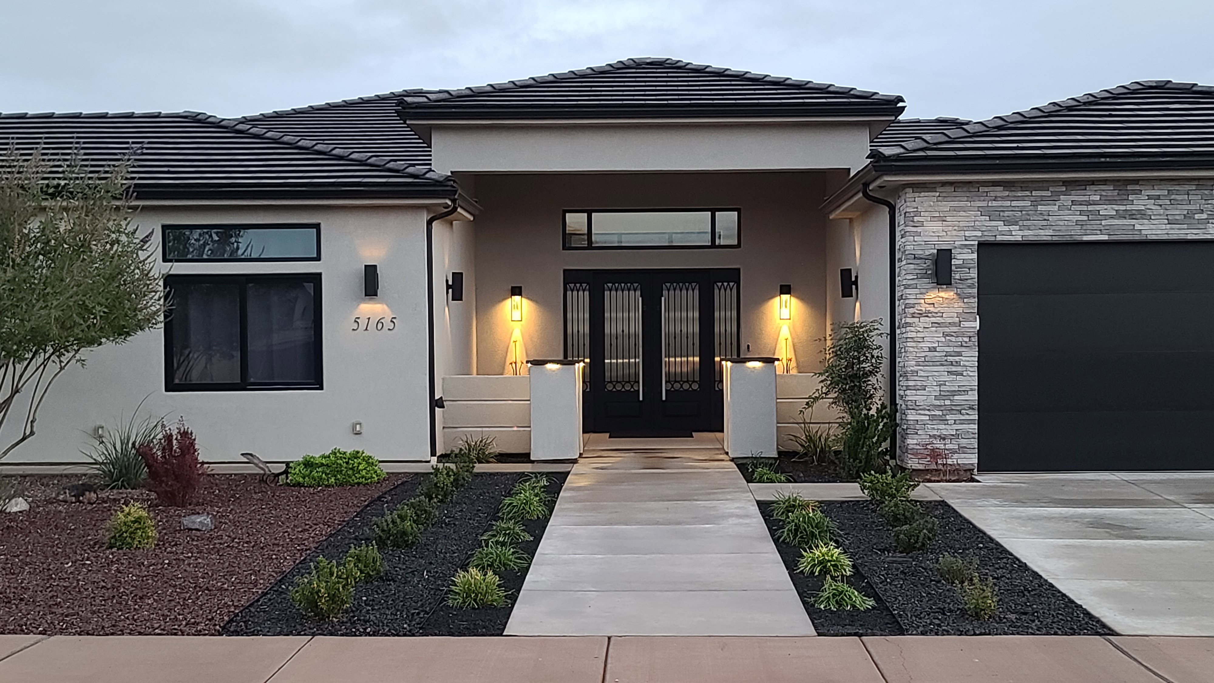 Contemporary stucco exterior with stone accents, a tile roof, and a prominent entry
